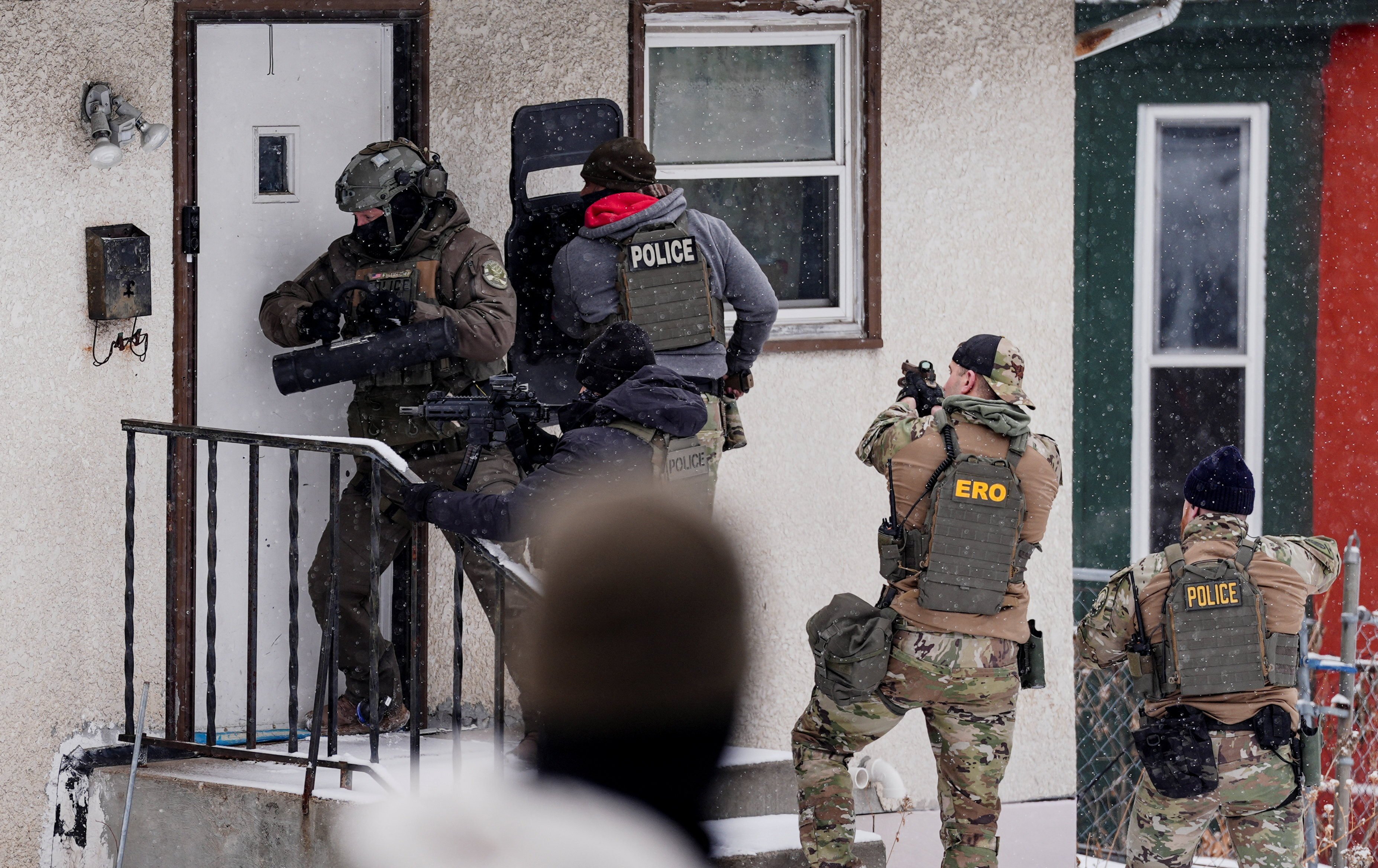 A law enforcement officer uses a battering ram to force entry into a home during an immigration raid in St Paul, Minnesota. Photo: Reuters