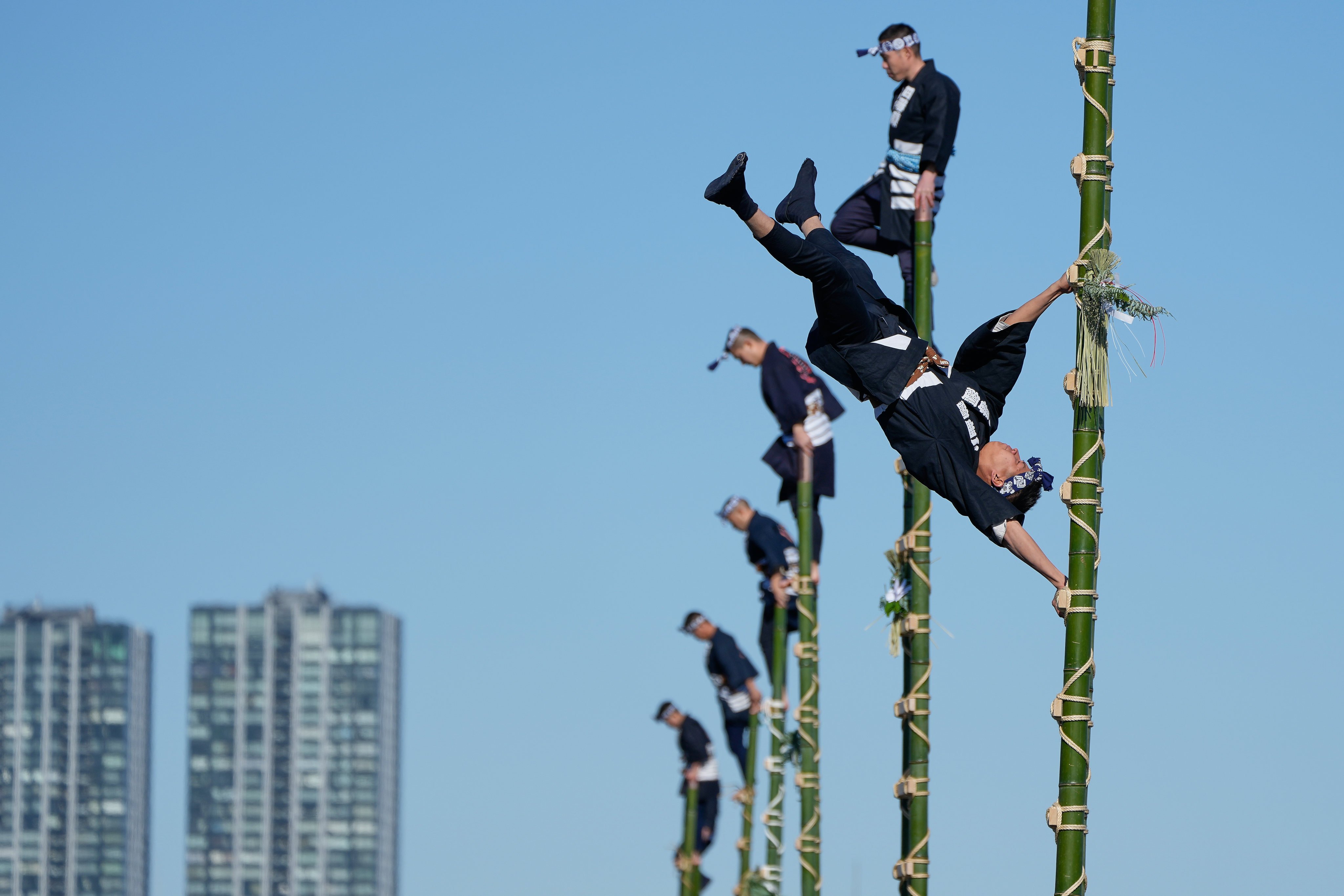 Members of a traditional firefighting preservation group perform stunts on bamboo ladders in Tokyo. Photo: AP