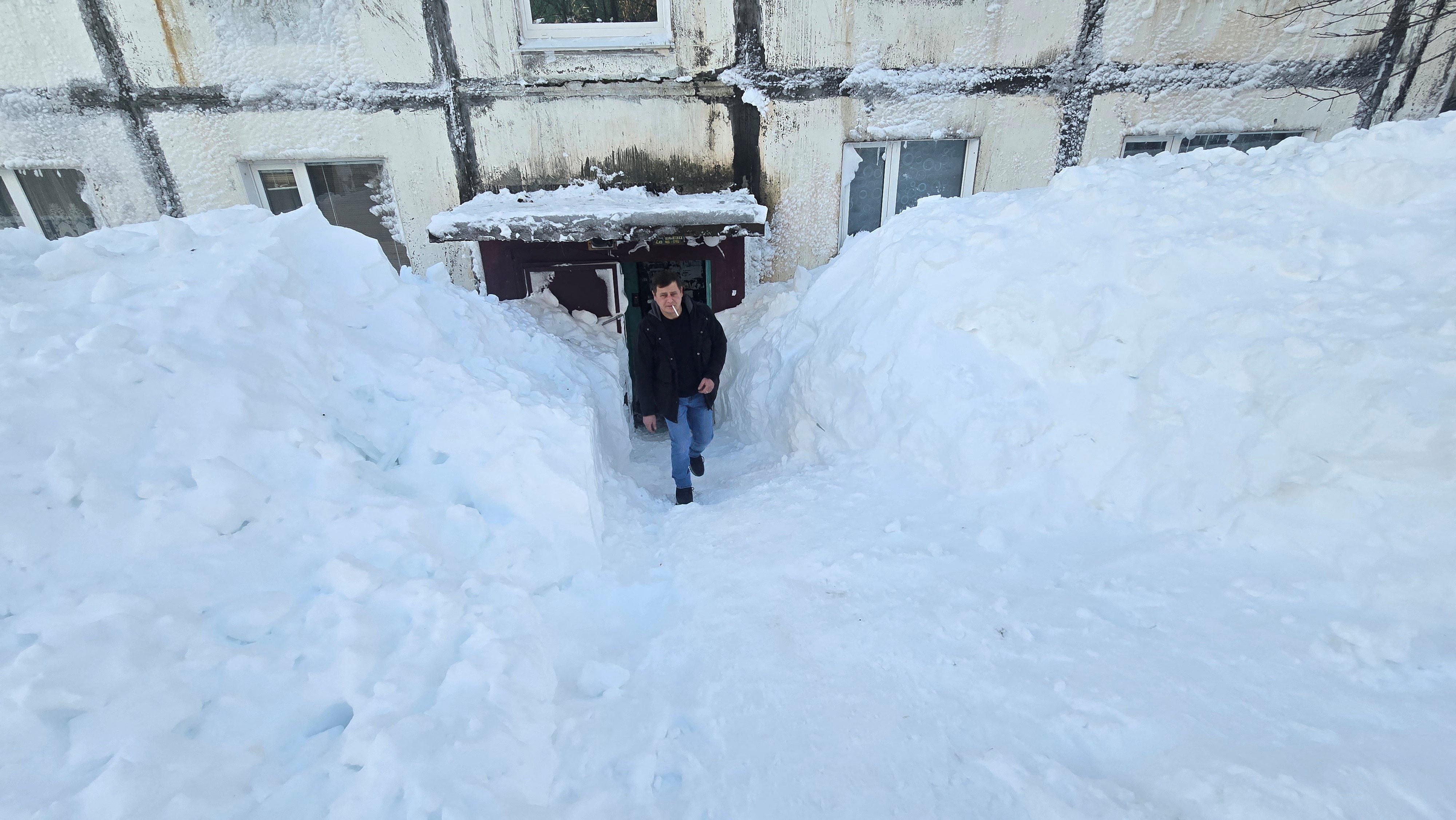 A man exits a residential block surrounded by snow. Photo: Lydmila Moskvicheva via Reuters