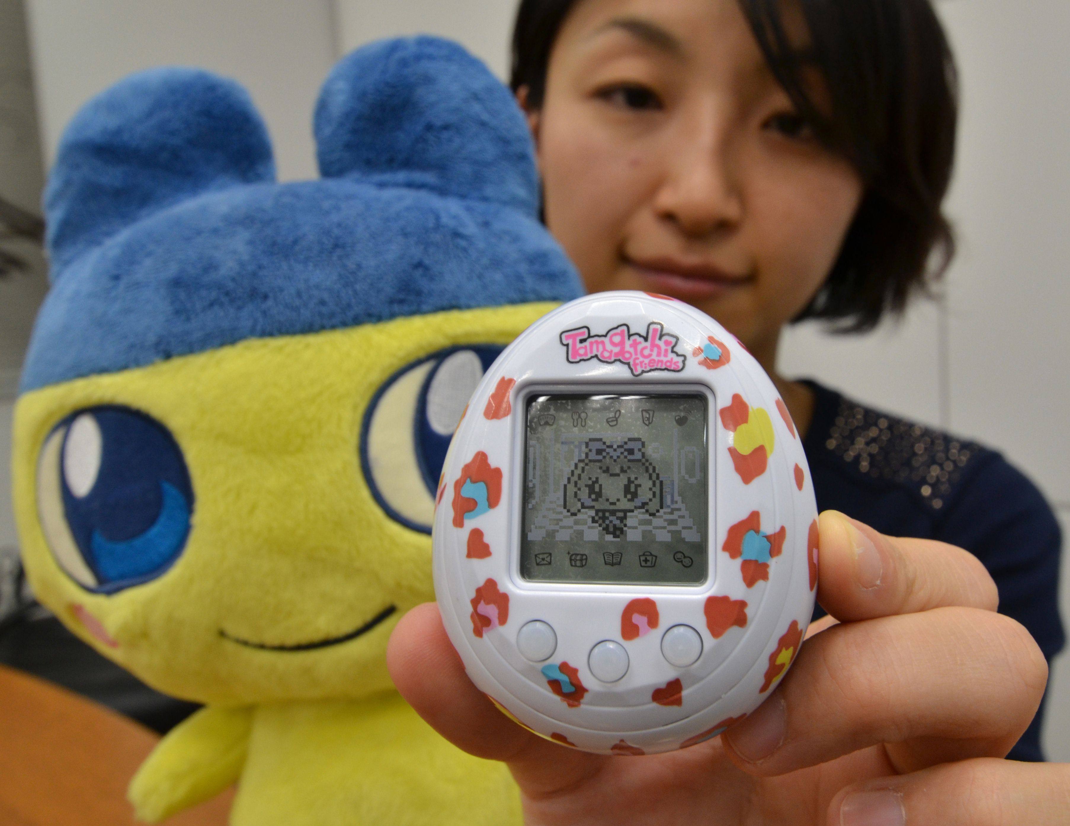 An employee of Japanese toy giant Bandai holds up a new “Tamagotchi Friends” release, an egg-shaped portable toy featuring cartoonlike characters, at the company’s headquarters in Tokyo. Photo: AFP