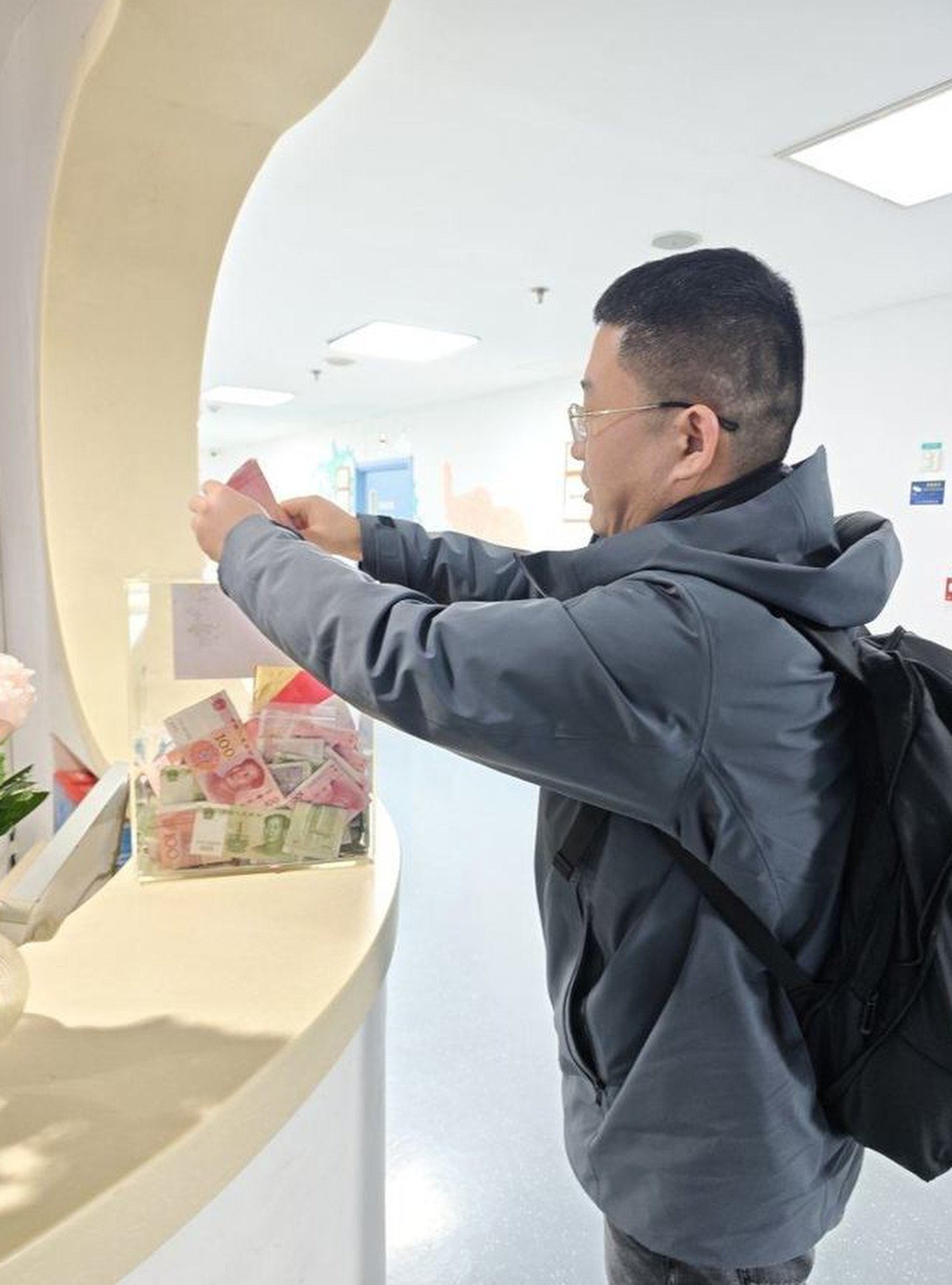 A generous member of the public puts some money in a donation box for the hospital. Photo: 163.com