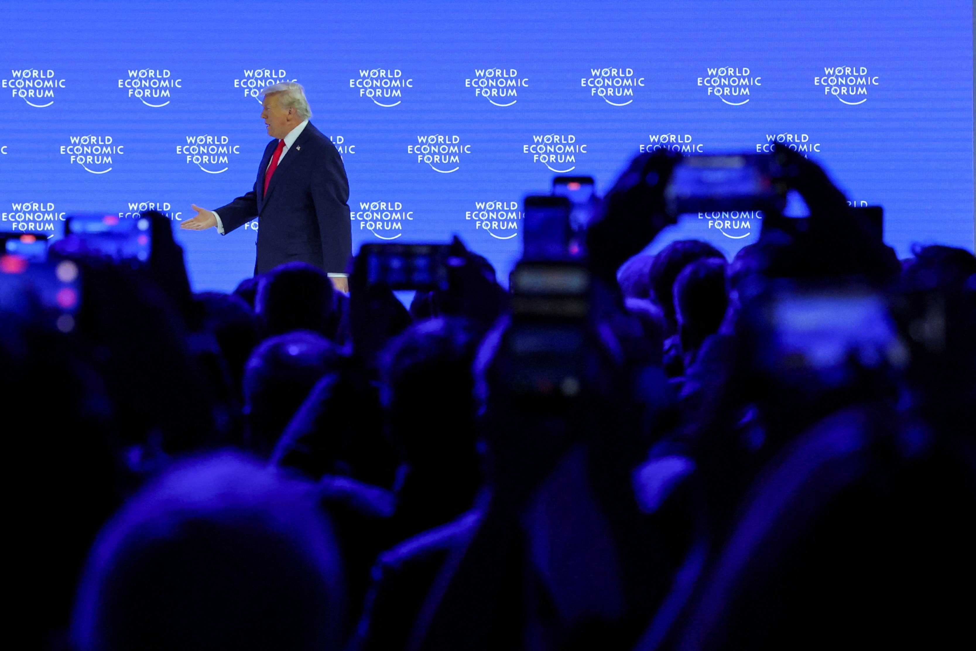 People use their mobile phones as Donald Trump walks across the stage before addressing the World Economic Forum meeting in Davos on Wednesday. Photo: Reuters