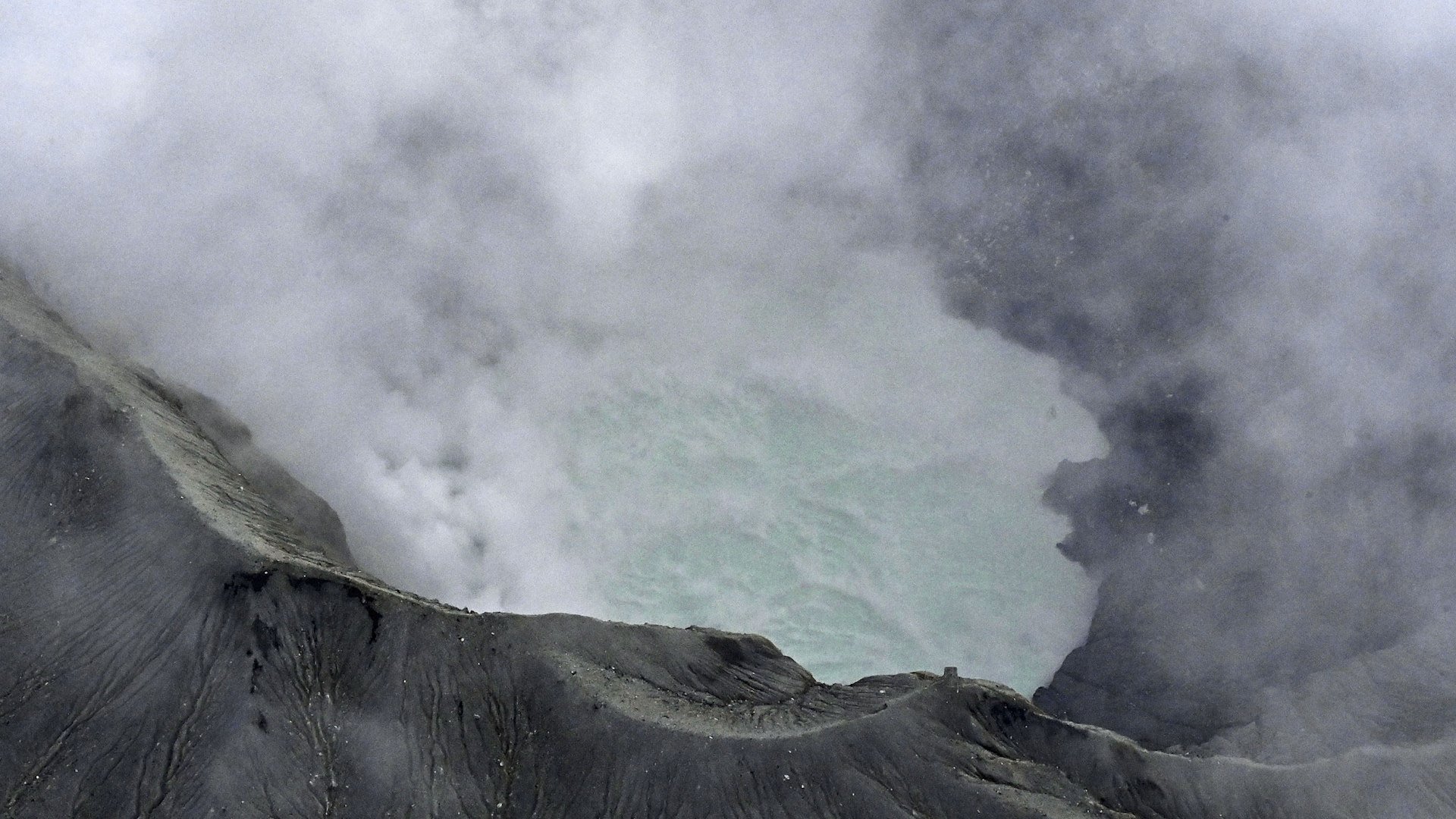 The sightseeing helicopter crashed into a steep crater on Mount Aso, with volcanic gases hindering recovery operations.