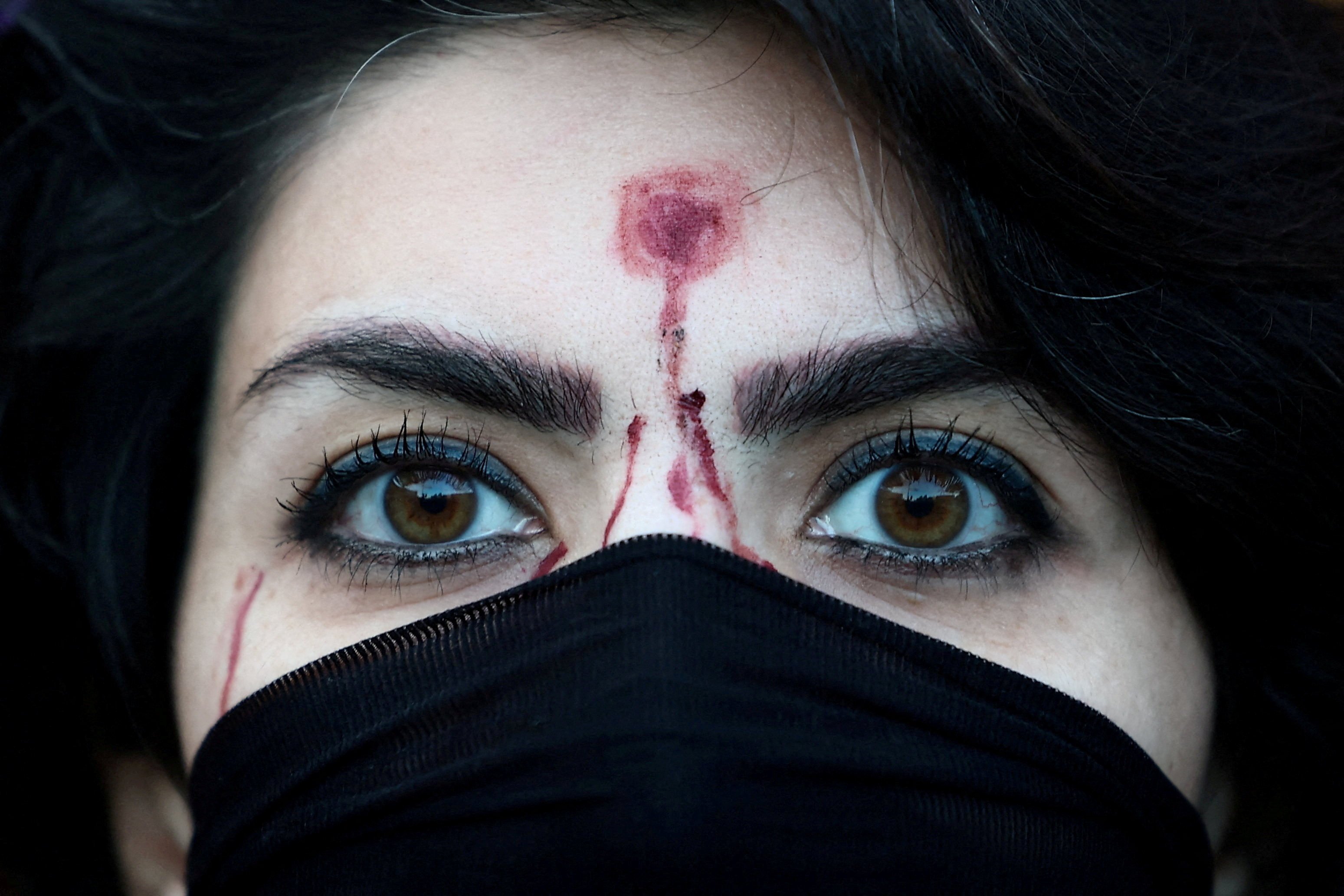 A woman with a mock-up of a gunshot bullet wound on her forehead participates in a rally in Rome on January 13 in support of nationwide protests in Iran. Photo: Reuters