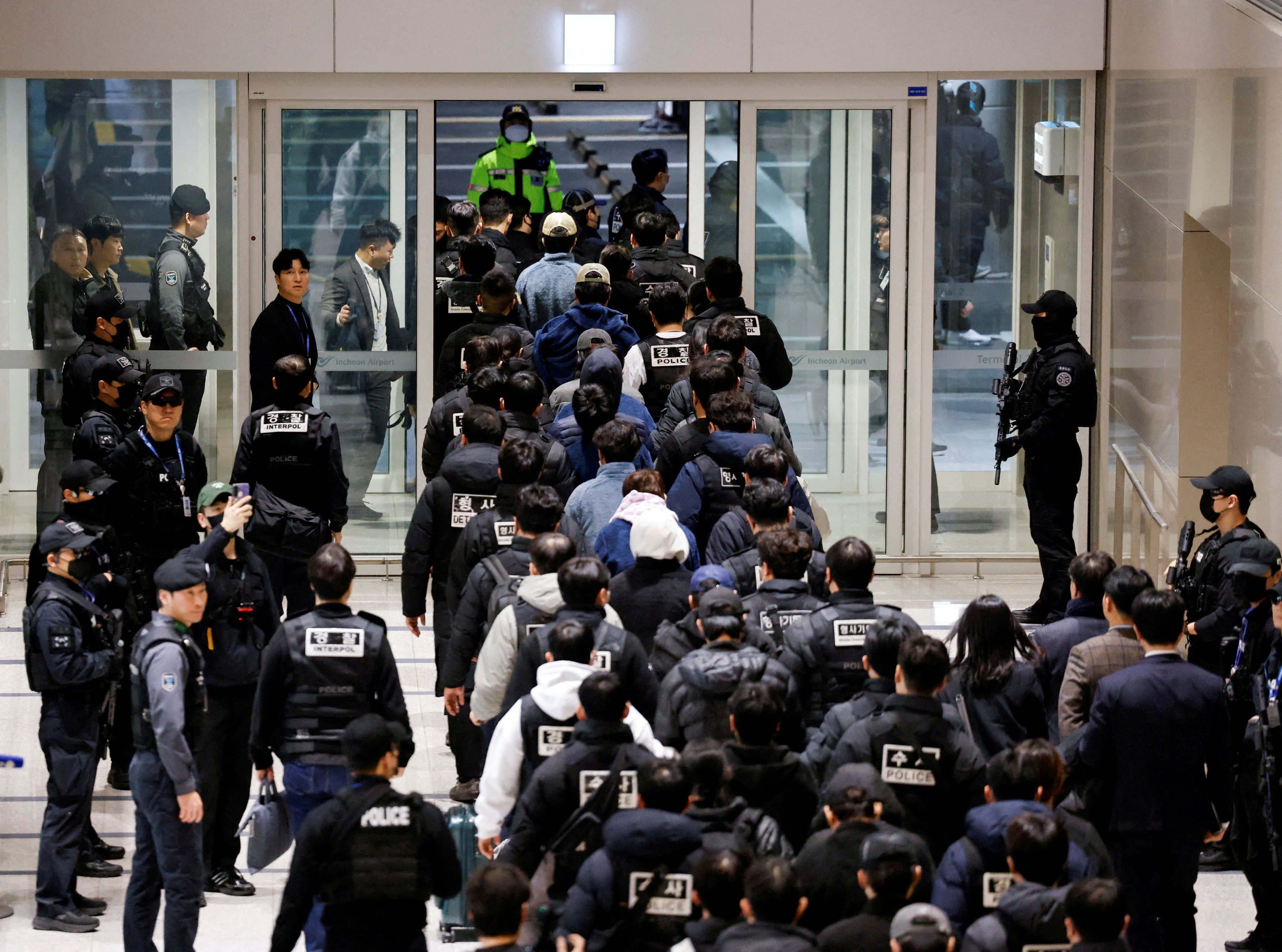 Police officers escort South Koreans allegedly involved in scam operations in Cambodia at Incheon International Airport on Friday. Photo: Reuters
