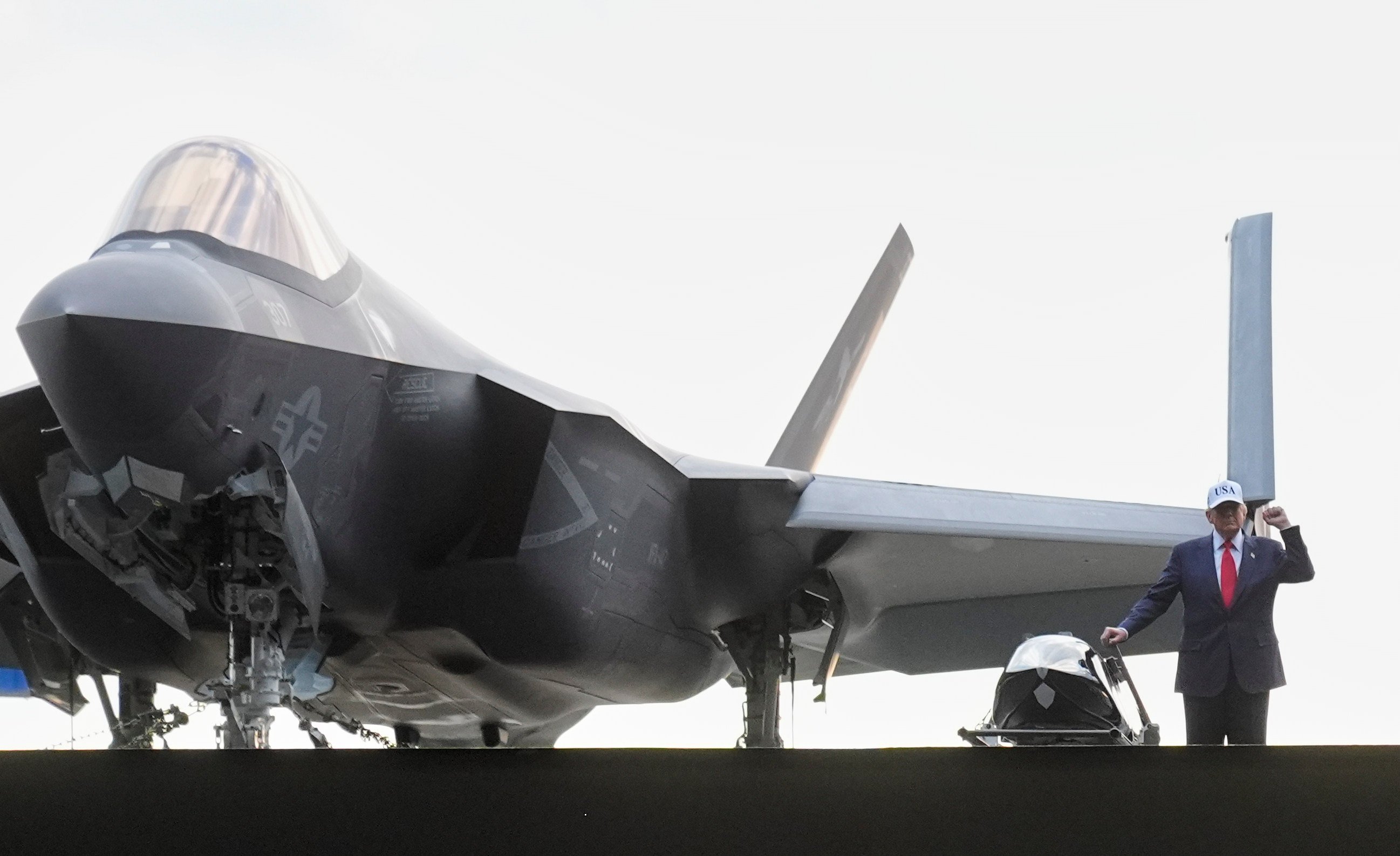 US President Donald Trump stands next to a fighter jet before speaking to members of the military on an aircraft carrier in October. Photo: AP