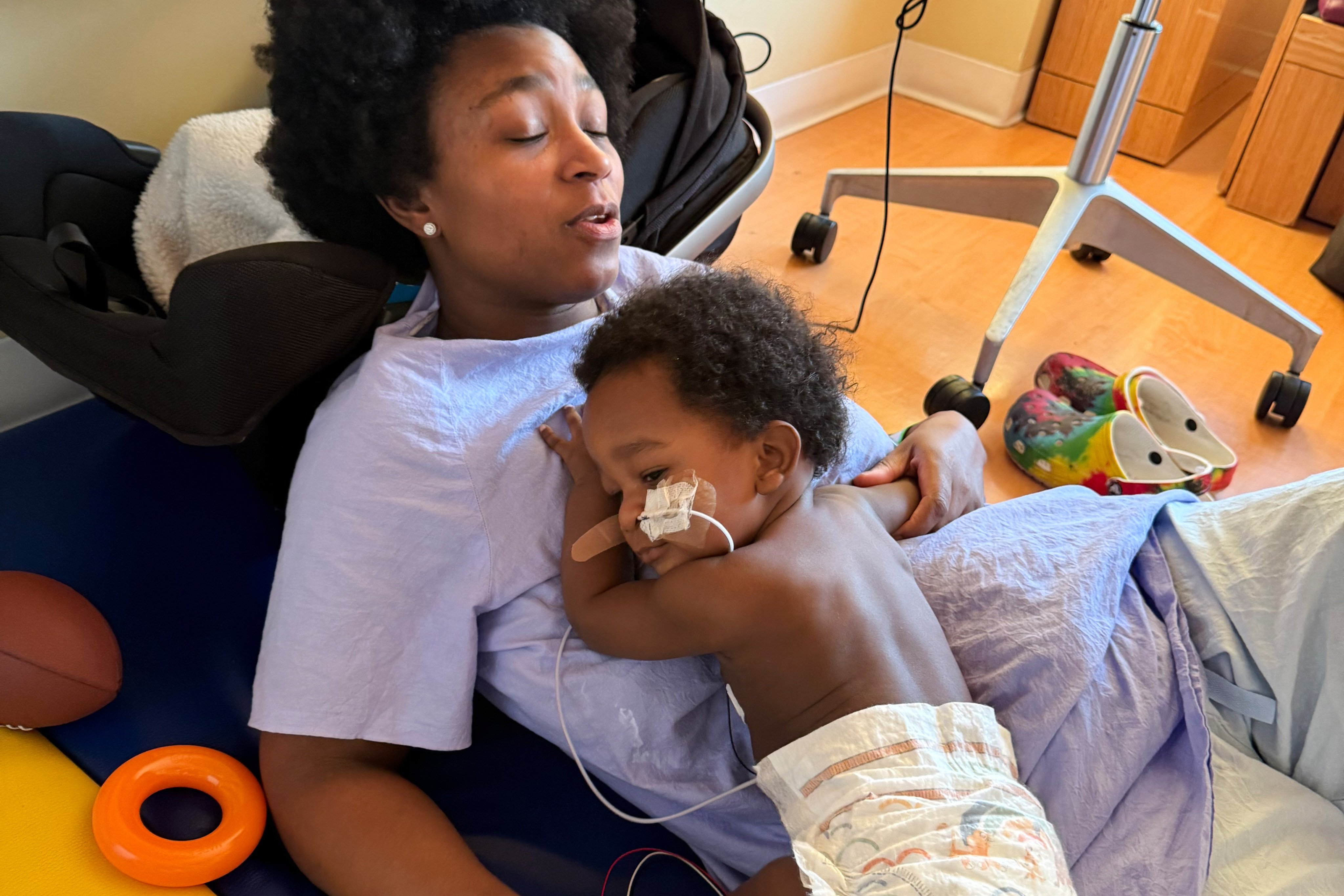 Ashaan Carter lies on his mother at a Portland children’s hospital during his treatment for infant botulism in November 2025 after drinking ByHeart baby formula donated to vulnerable families. Photo: AP