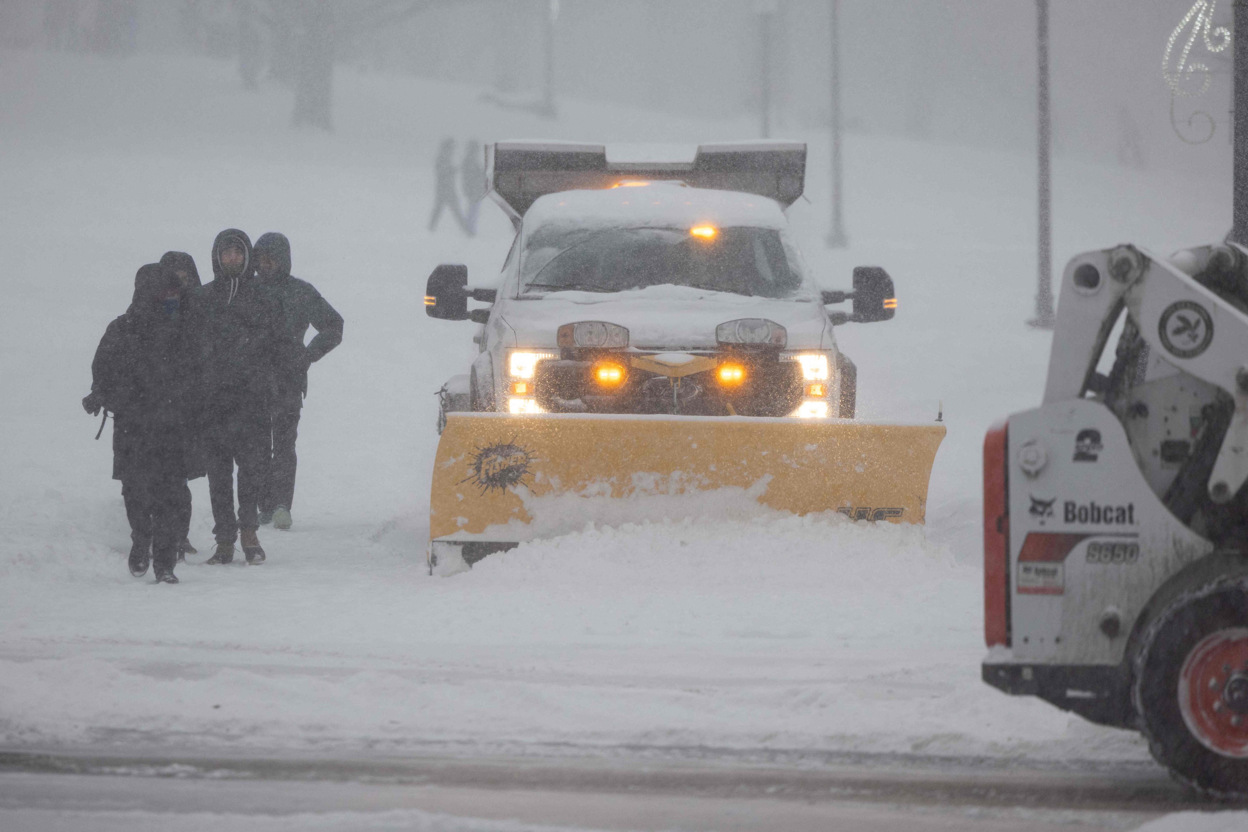 Vehicles work to clear snow alongside pedestrians on the Boston Common during heavy snow on Sunday. Photo: Getty Images/AFP