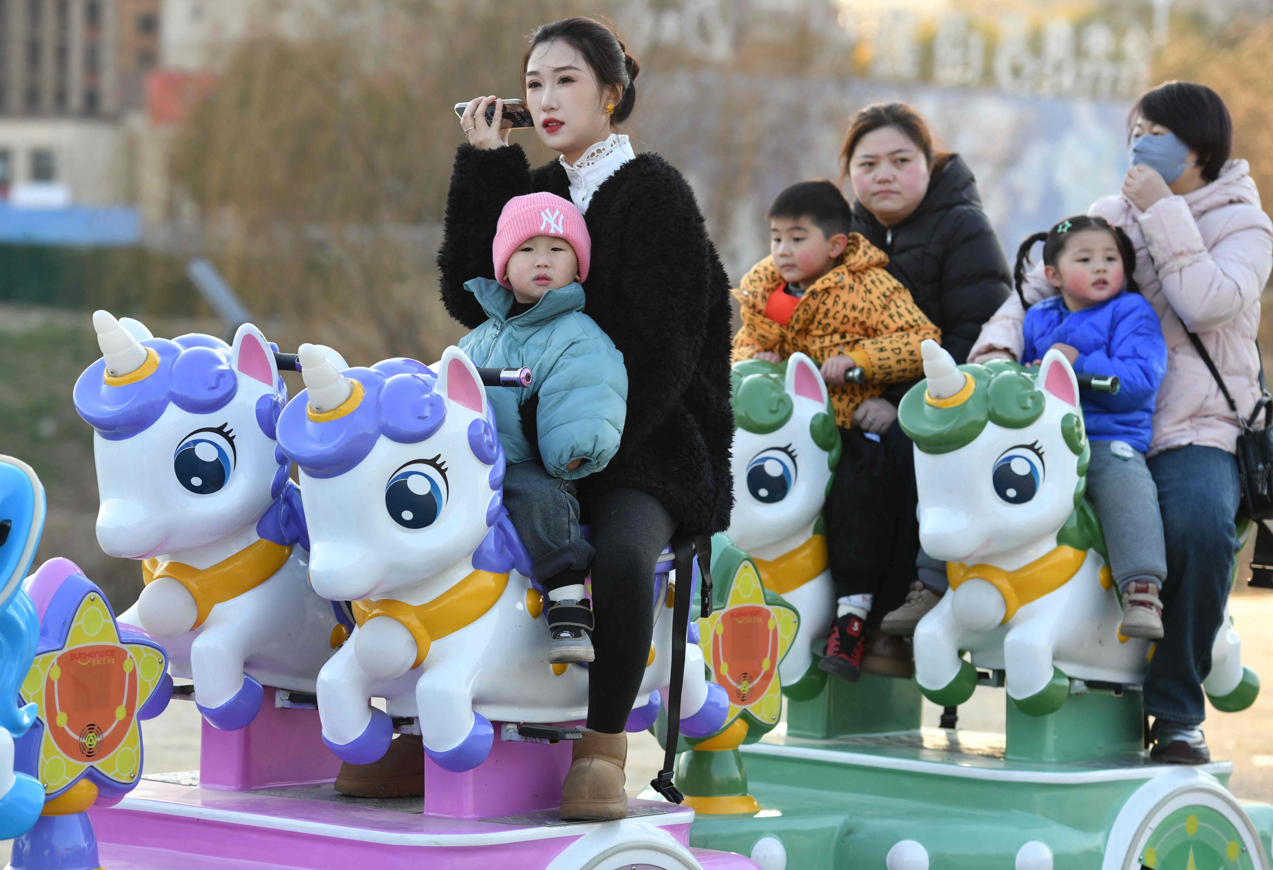Children and adults take rides in a park in Fuyang, Anhui province in 2025. Photo: AFP