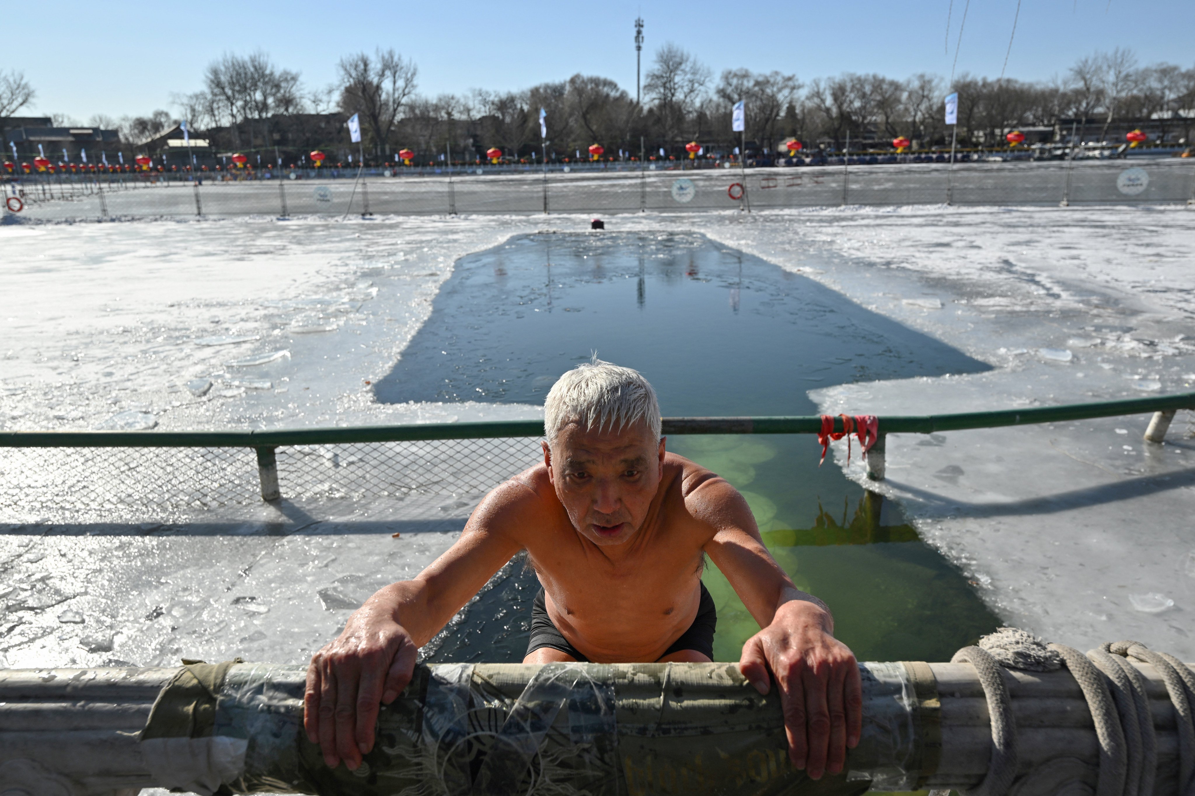 A winter swimming enthusiast reacts after swimming at the Houhai Lake of the Shichahai scenic area in Beijing on January 20, 2026. Every winter dozens of locals add to their daily routine a frigid lap in the icy waters of Shichahai, a sprawling lake in the center of the Chinese capital. (Photo by Adek BERRY / AFP)