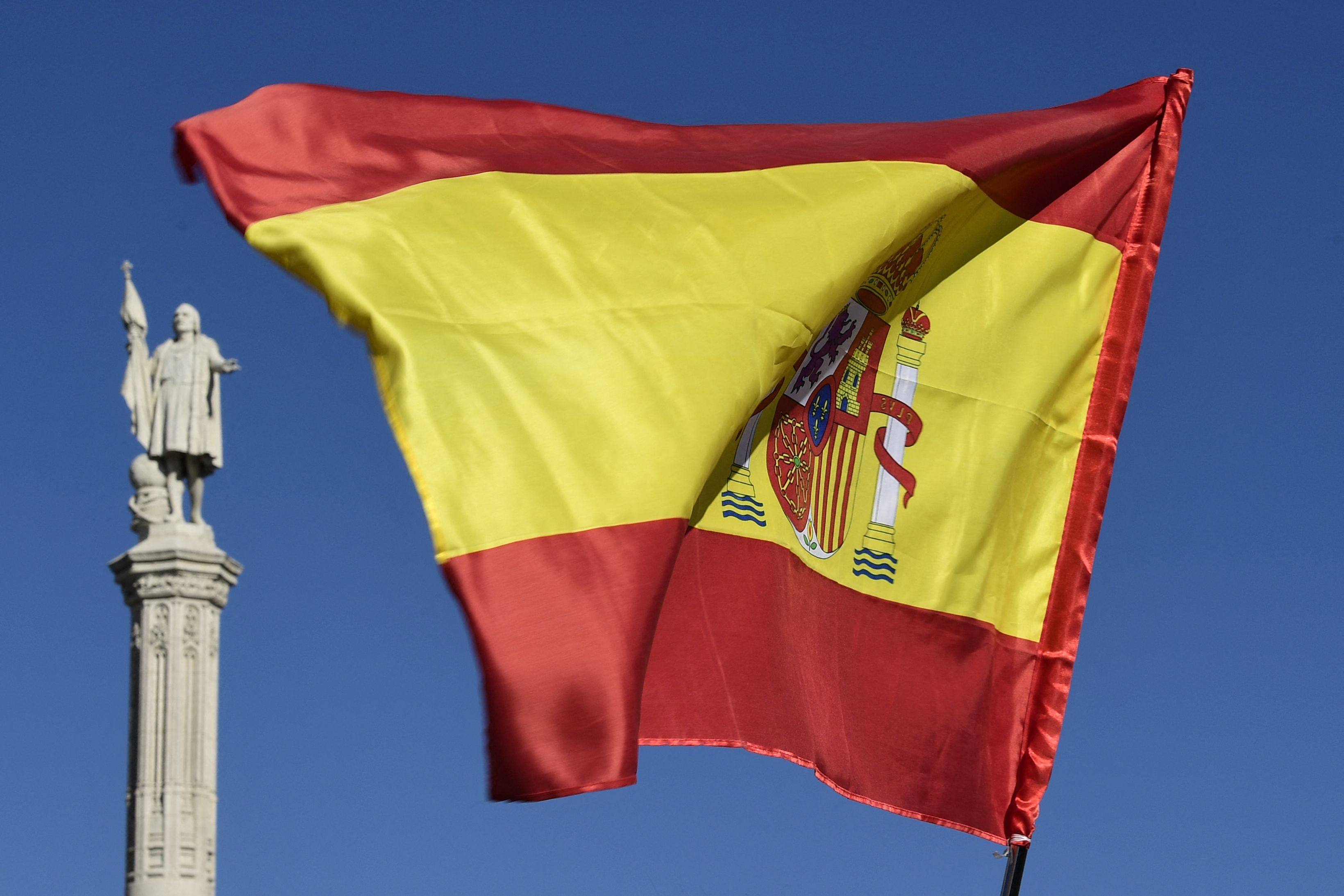 A Spanish flag flies by the Christopher Columbus monument in Madrid. On Tuesday, Spain’s left-wing government approved a decree to legalise thousands of undocumented migrants. Photo: AFP