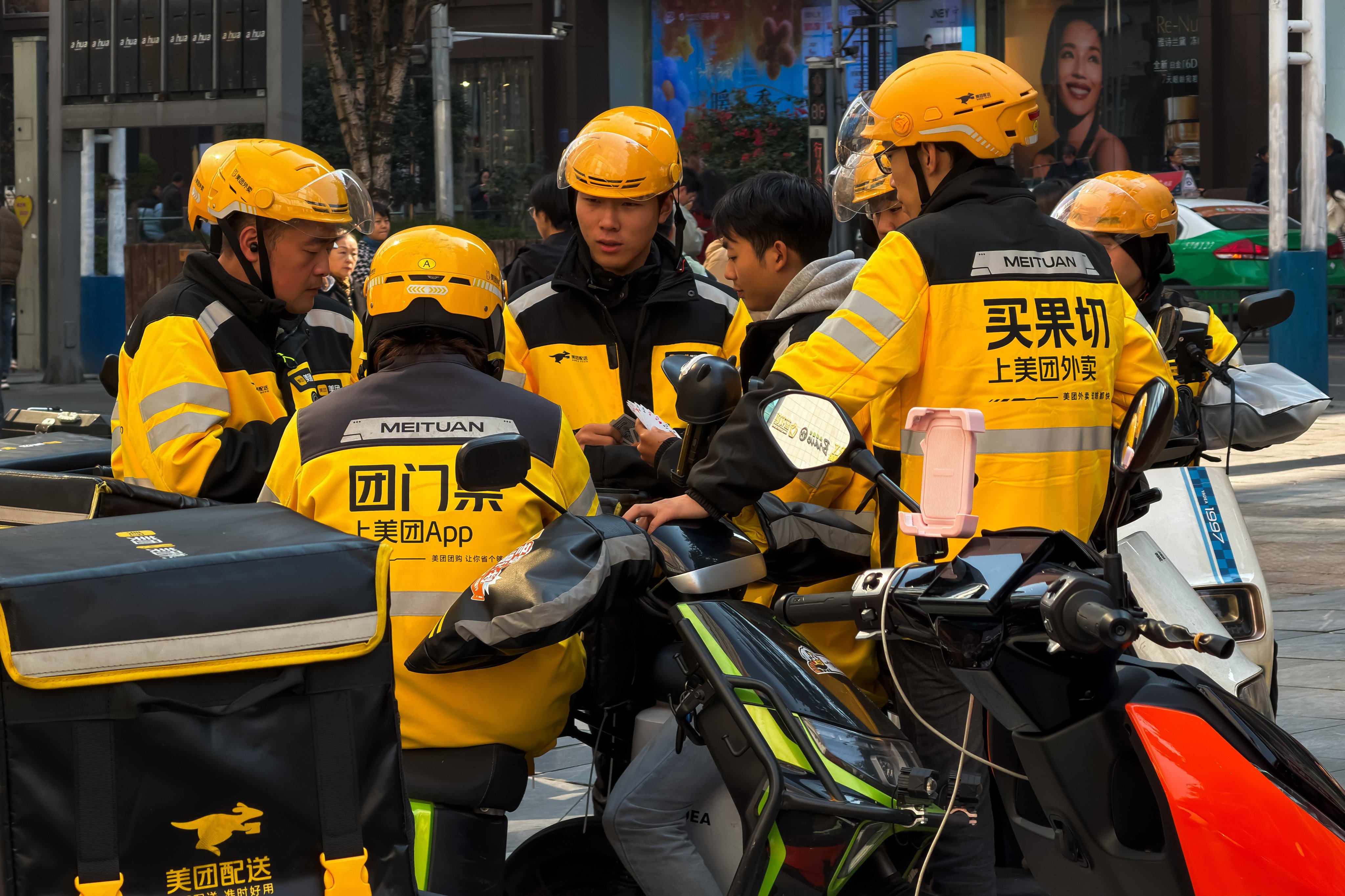 Meituan delivery riders gather during a break in a commercial district in Chongqing, China, on November 21, 2025. Photo: Getty Images