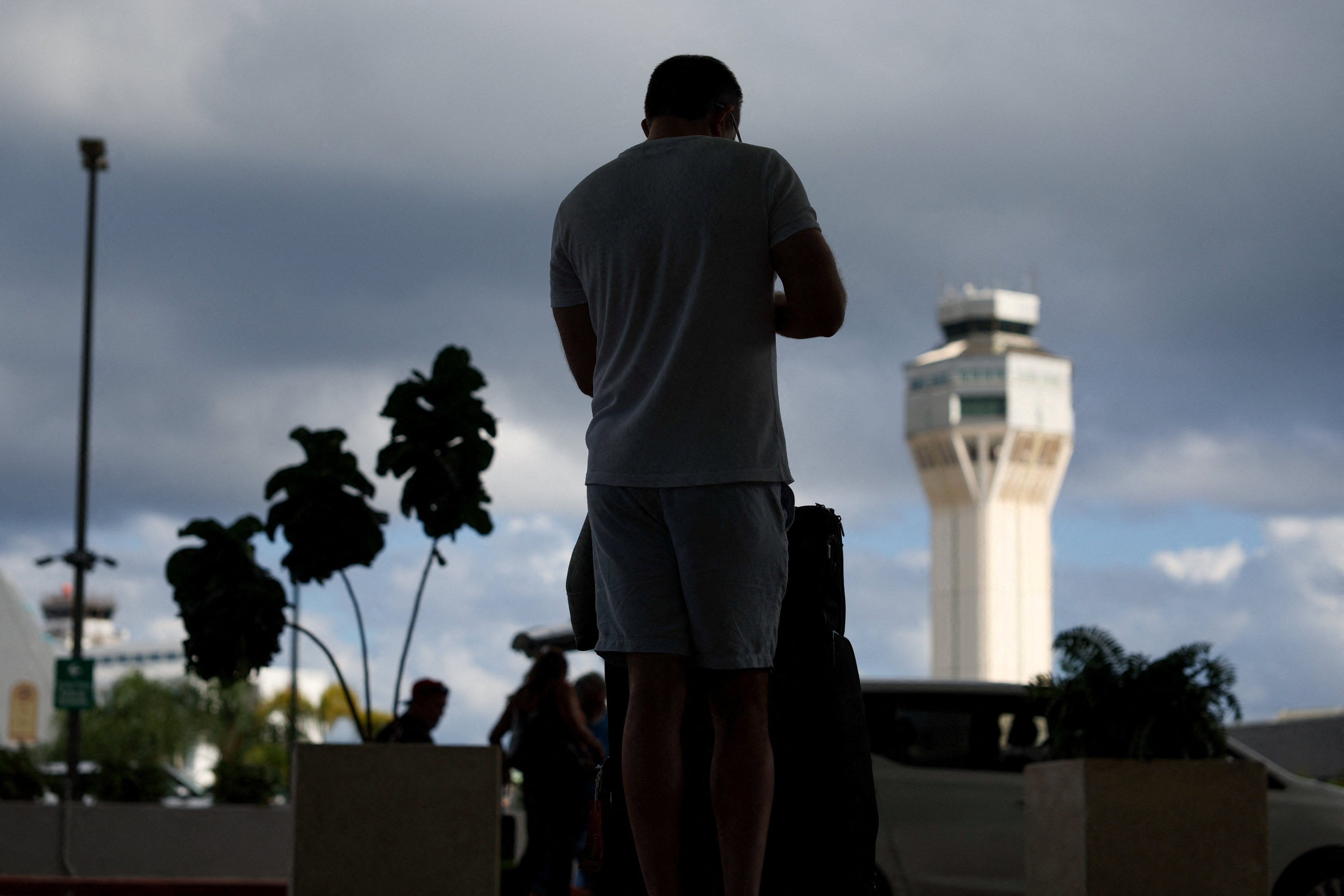 A passenger stands with his luggage at an airport near San Juan, Puerto Rico, on January 3 after airspace was closed due to US strikes on Venezuela. Photo: Reuters