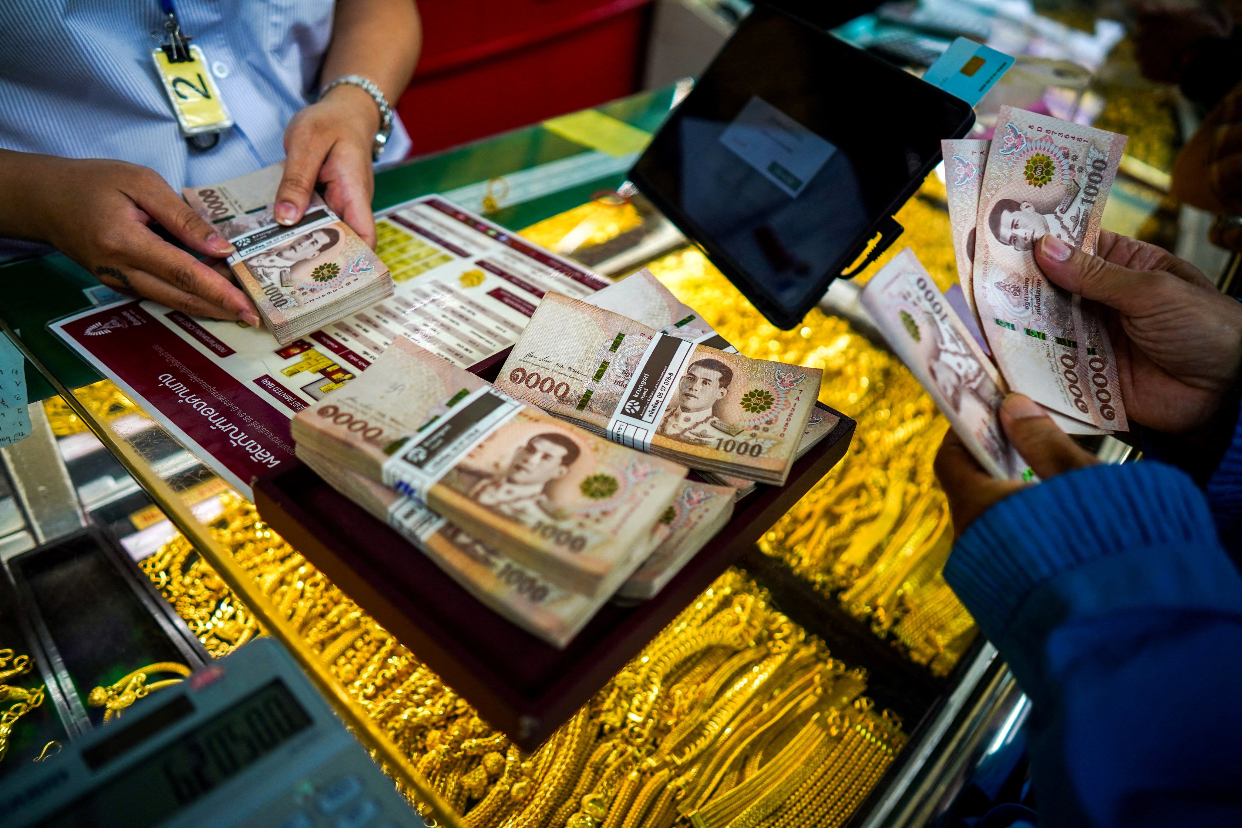 A customer and an employee count Thai baht banknotes at a gold shop in Bangkok’s Chinatown, Thailand, on October 9, 2025. Photo: Reuters