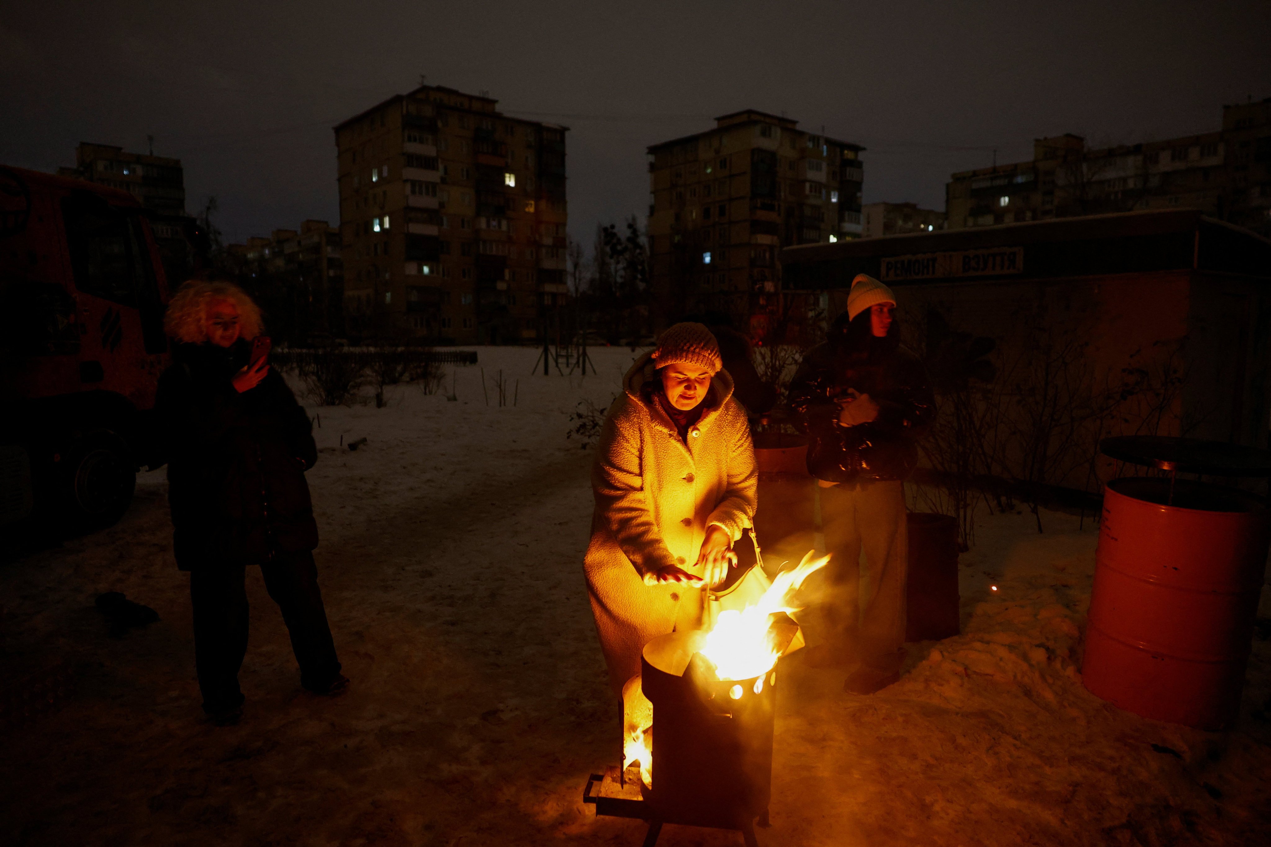 A resident warms up next to fire during a blackout in Kyiv, Ukraine, on Monday. Photo: Reuters