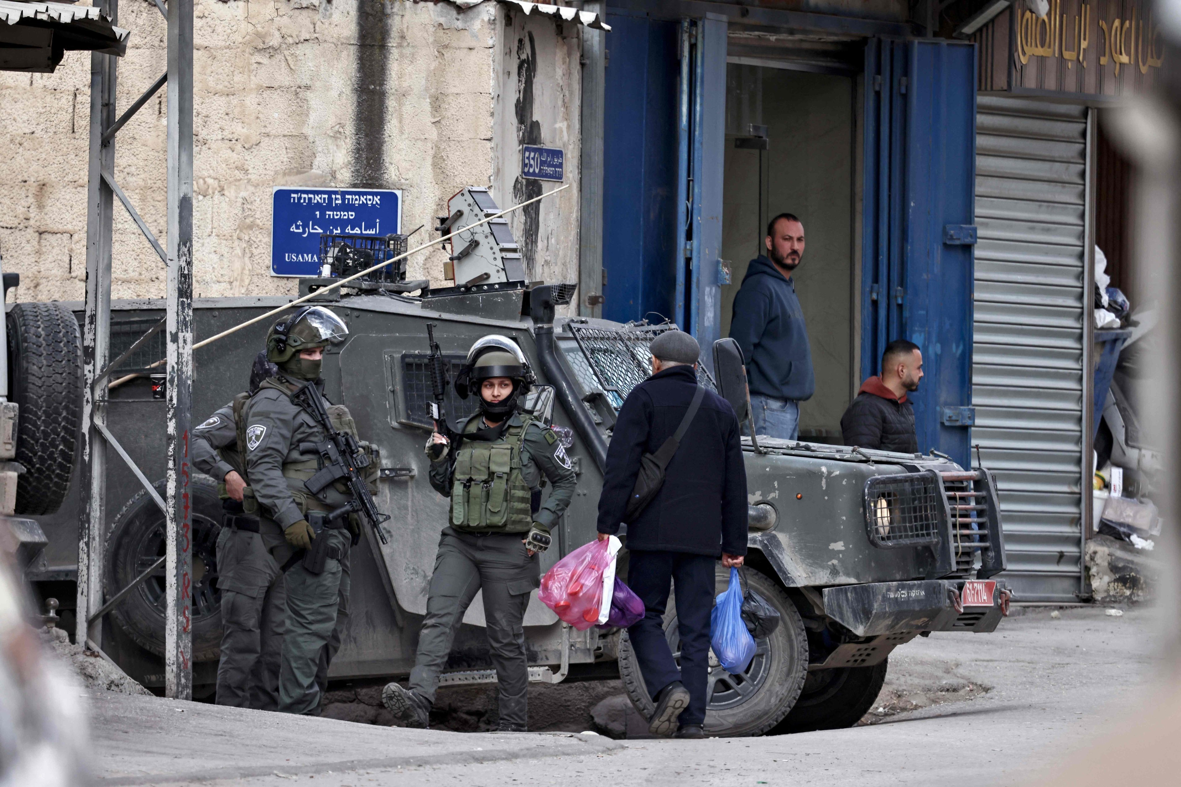 A Palestinian man carries his shopping past Israeli security forces during in Kafr Aqab in the Israeli-occupied West Bank on Wednesday. Photo: AFP