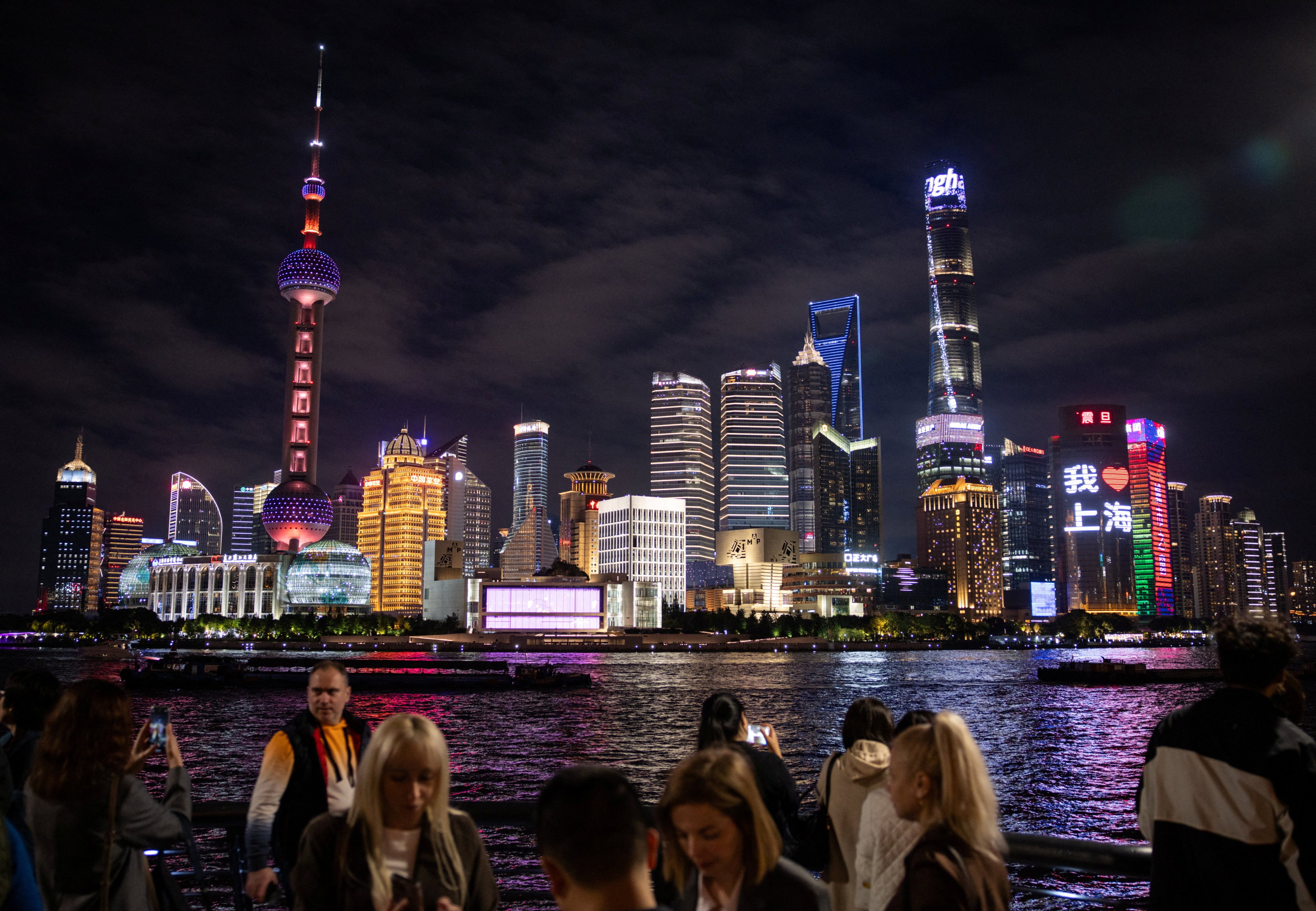 People walk at the Bund by the Huangpu river with skyscrapers of the Lujiazui financial district in the background, in Shanghai. Photo: Reuters