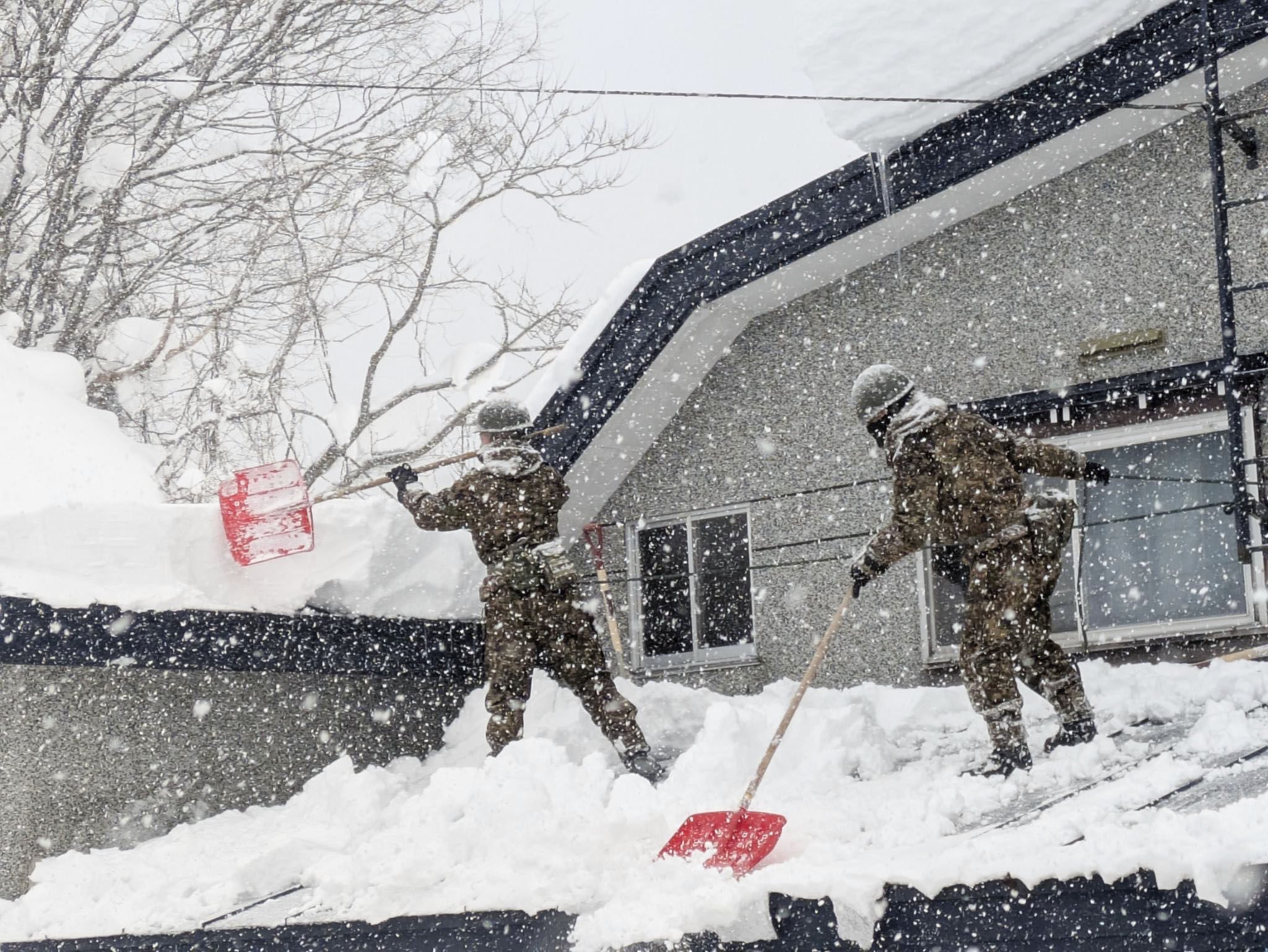 Japanese military personnel remove snow from a rooftop in Aomori, northeastern Japan, on Monday. Photo: Kyodo
