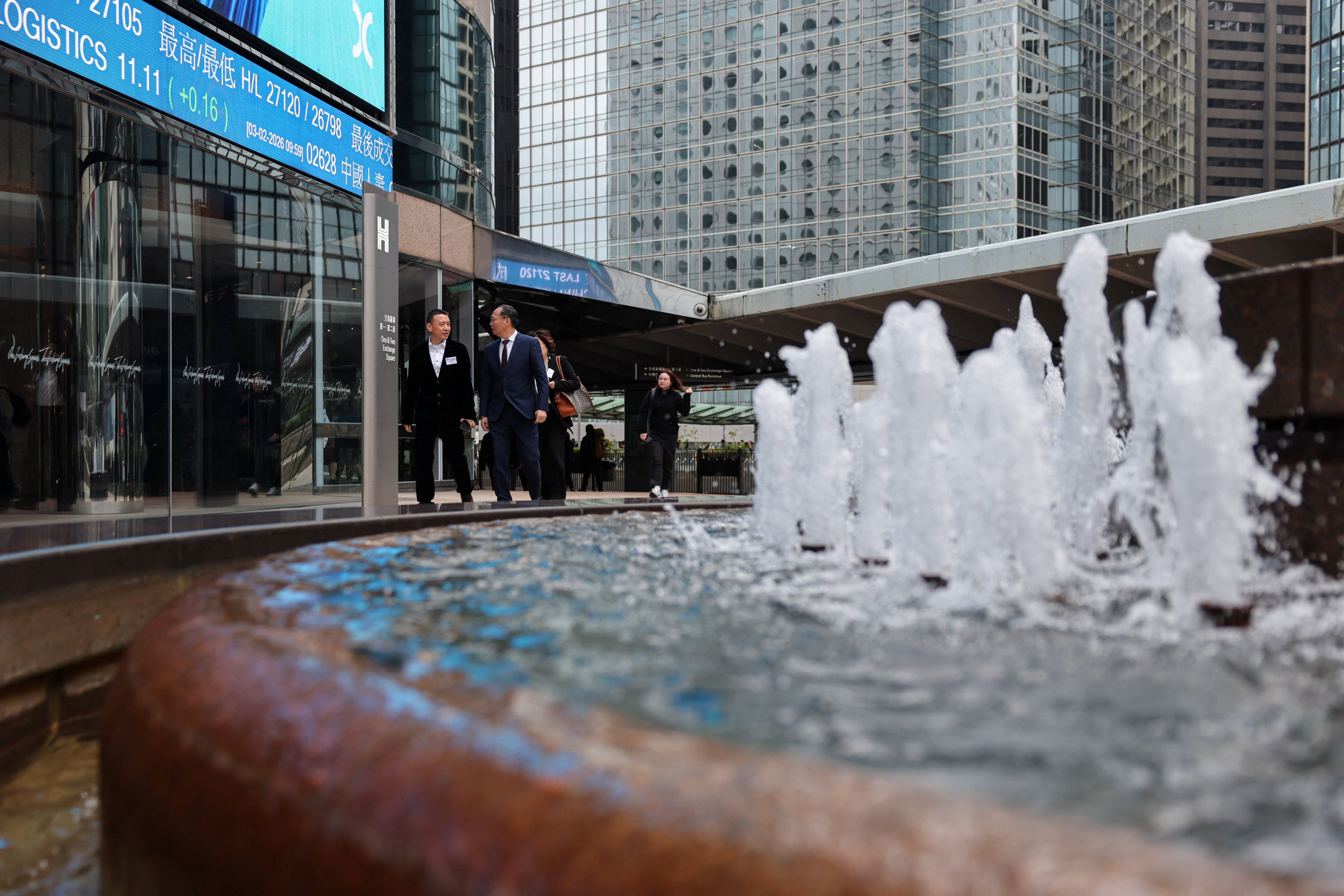 People walk near screens displaying stock information at Exchange Square in Hong Kong, home of the city’s bourse operator, on February 3, 2026. Photo: Reuters