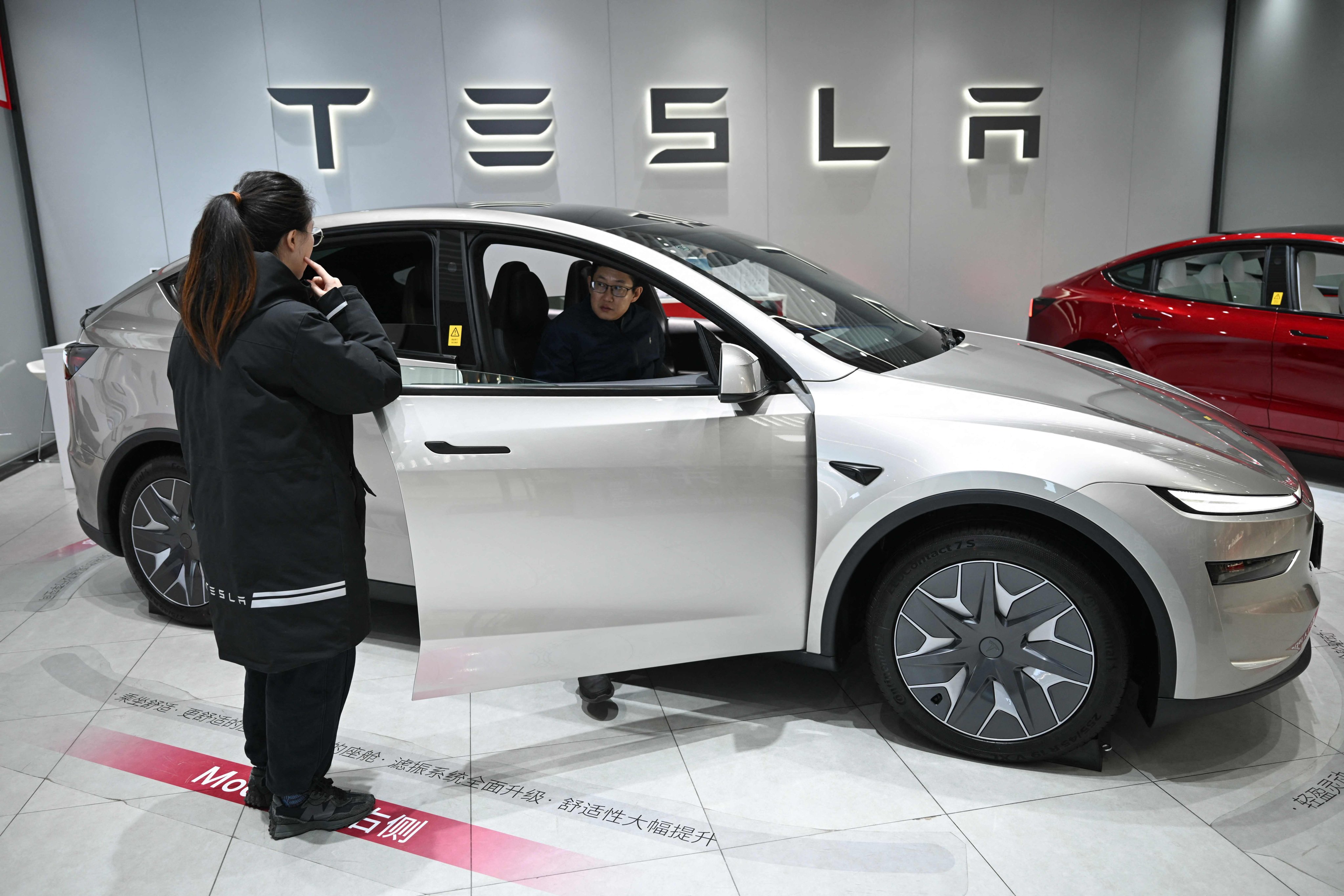 A potential buyer discusses a Tesla YL with a staff member in a showroom in Beijing on February 3, 2026. Photo: AFP