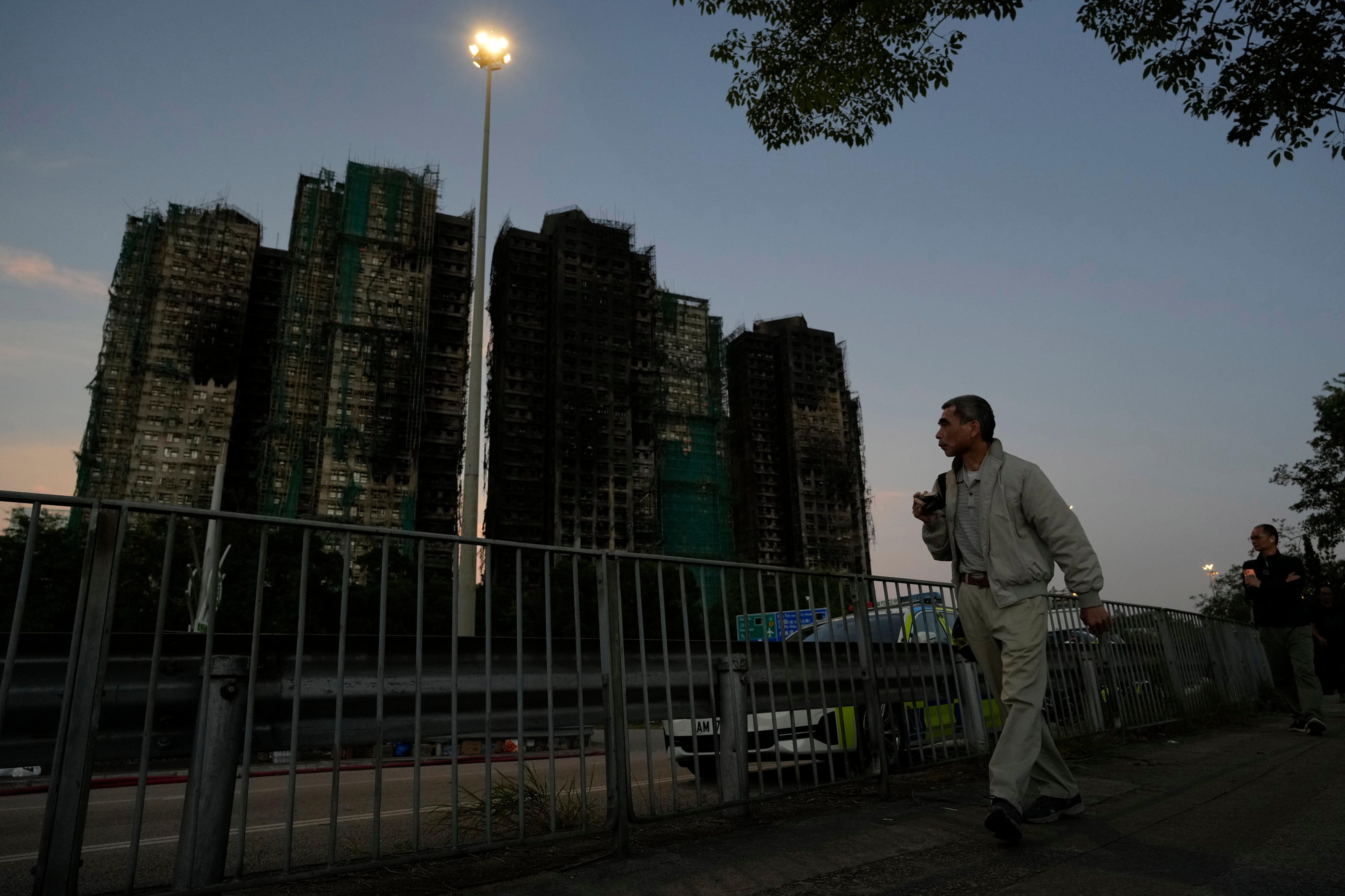 A man walks past burnt buildings after the deadly fire at Wang Fuk Court in Tai Po district on November 28 2025. Photo: AP