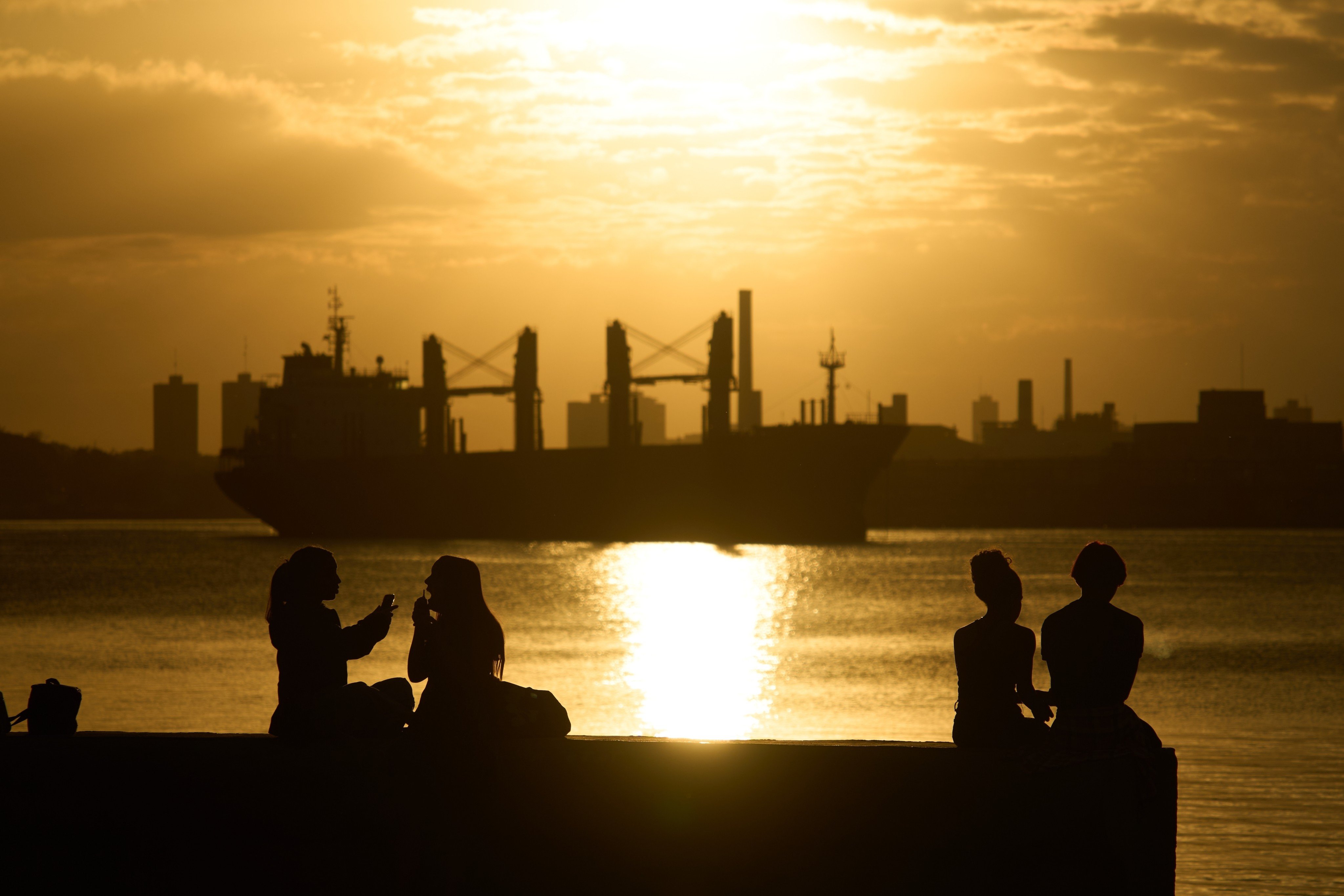 People sit on the seawall in Regla, Cuba, across the bay from Havana. Photo: AP