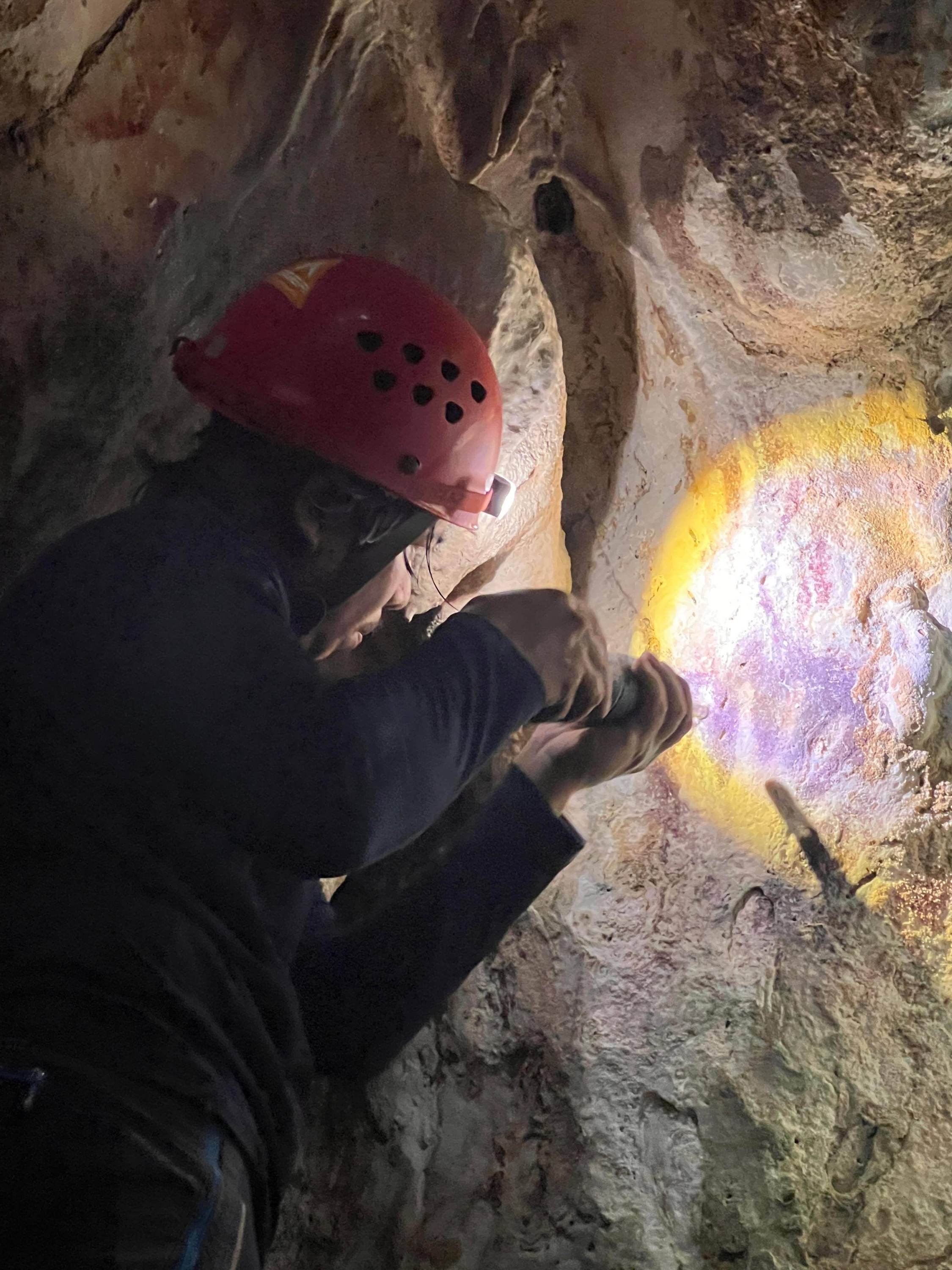 Scientist Adhi Agus Oktaviana studies handprints on the walls of a cave in Sulawesi, Indonesia. Photo: Maxime Aubert/AP