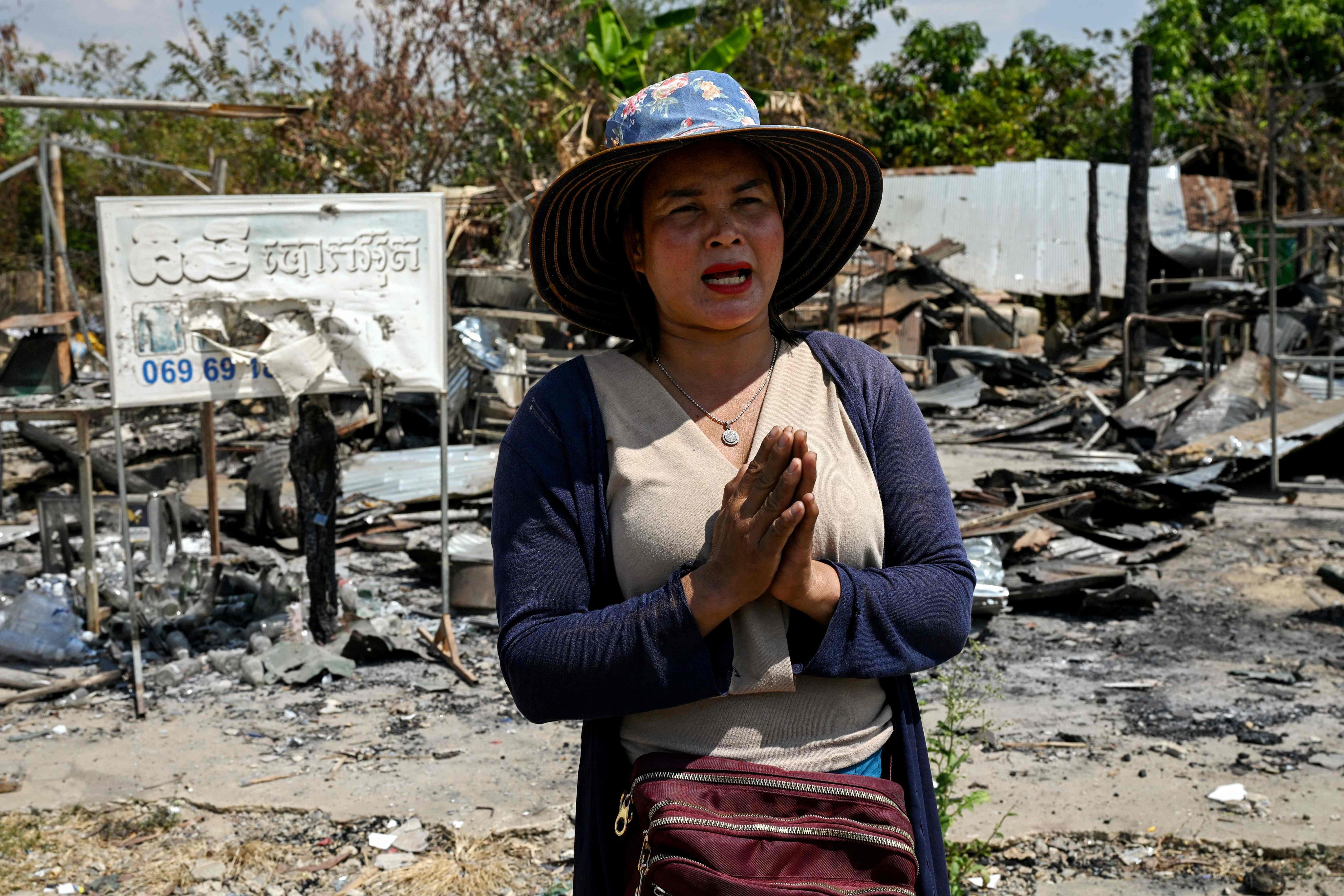 Meas Kimheng gestures in front of her house, damaged during clashes between Thai and Cambodian soldiers, in Prey Chan village in Banteay Meanchey province on Thursday. Photo: AFP