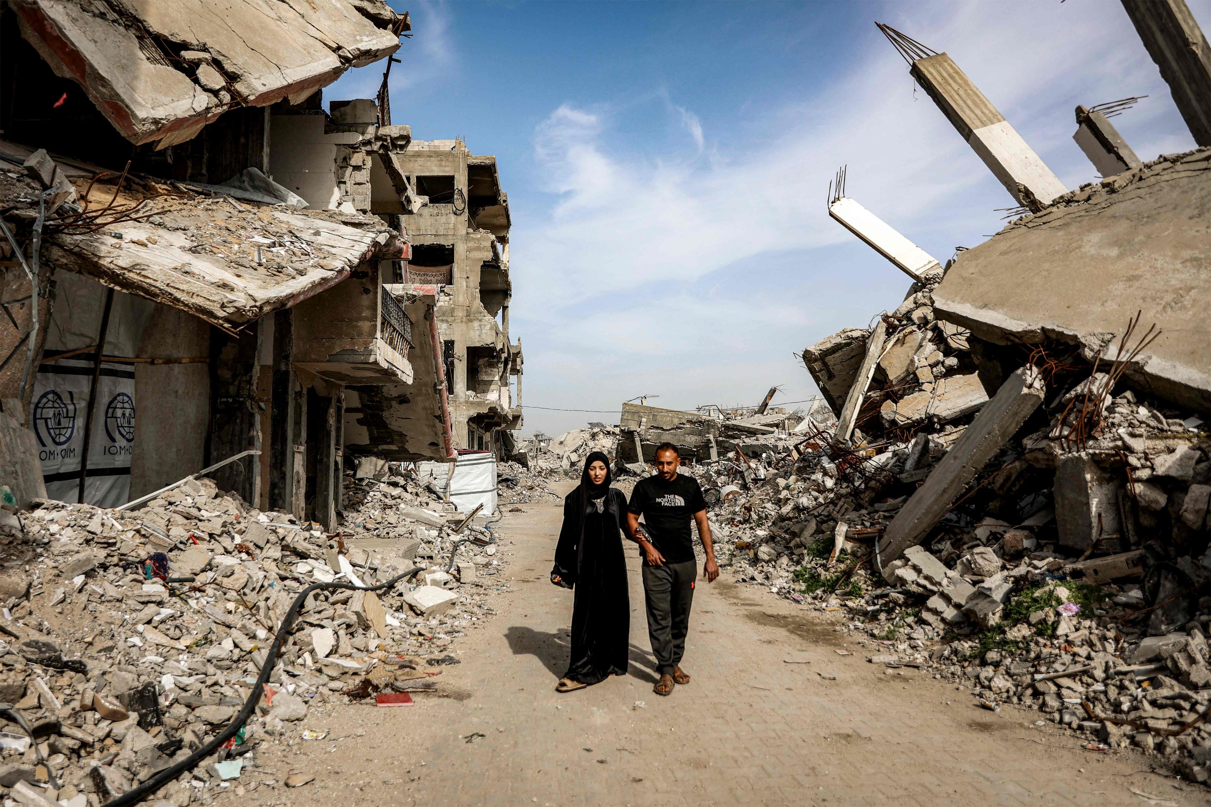 Etedal Rayyan, who recently returned back to Gaza from Egypt through the Rafah border crossing, walks with her husband past the rubble of destroyed buildings in the Jabalia camp for Palestinian refugees in the northern Gaza Strip on Sunday. Photo: AFP