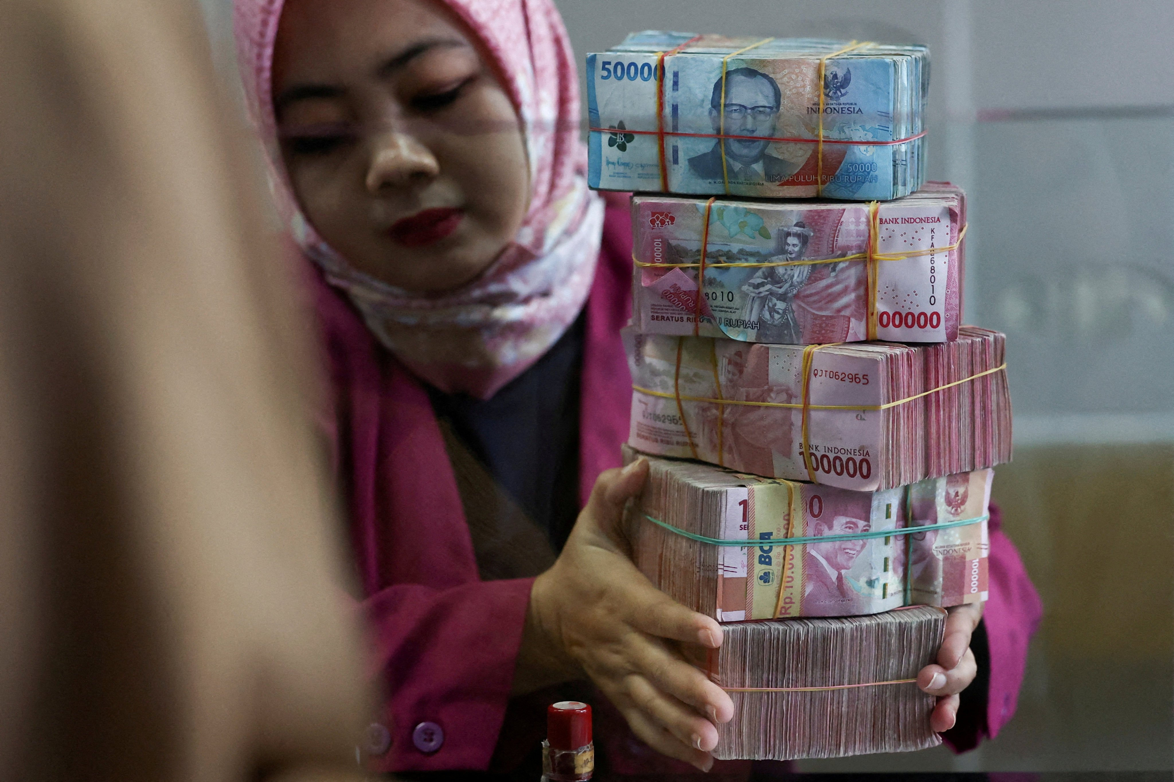 A teller prepares rupiah bank notes at a money changer in Jakarta, Indonesia, on April 9, 2025. The Southeast Asian nation has one of the world’s largest populations without access to banking services. Photo: Reuters