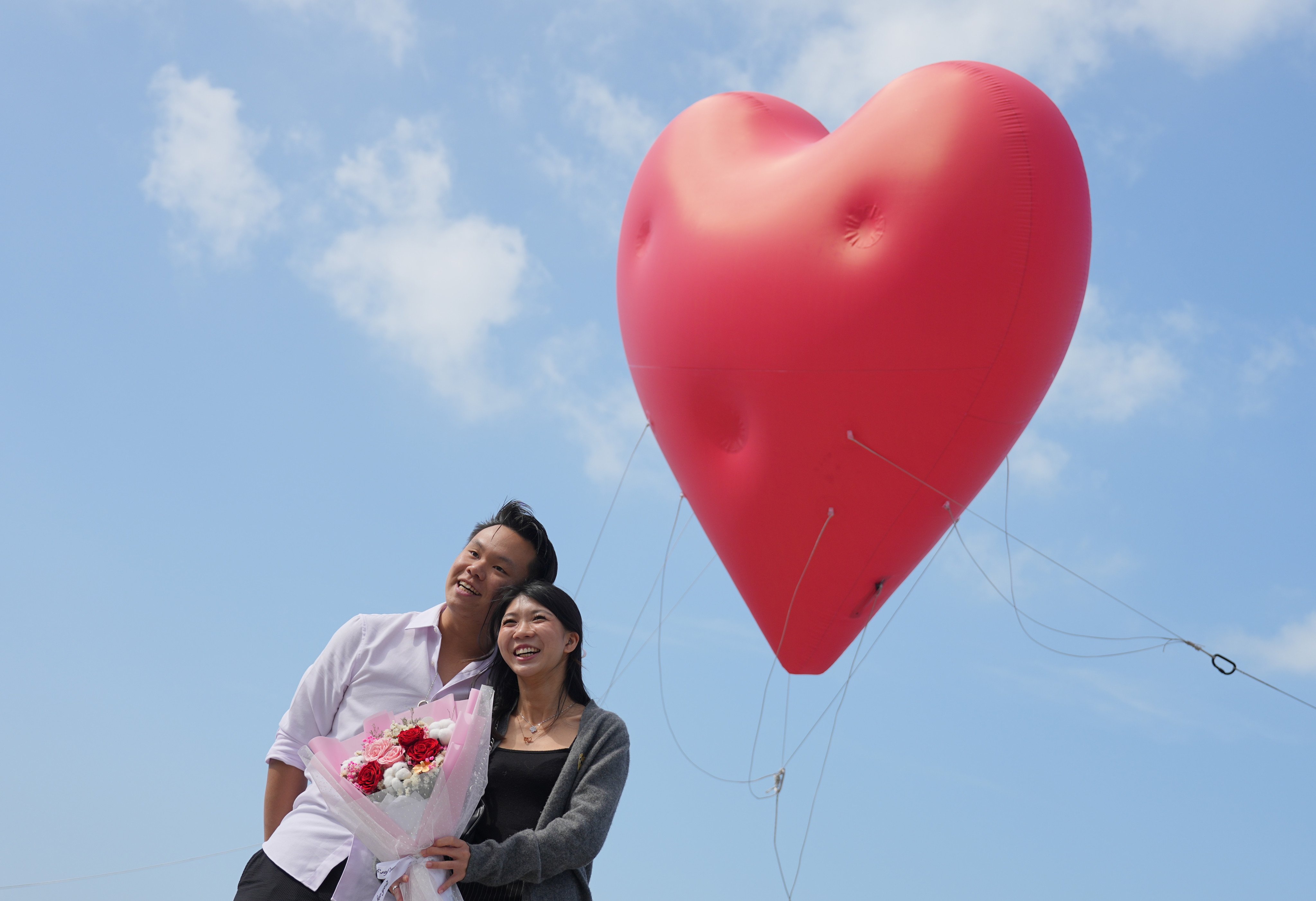 A couple stand in front of the “Chubby Hearts Hong Kong” art installation by Anya Hindmarch in Kennedy Town, Hong Kong, on Valentine’s Day in 2024. Photo: Eugene Lee