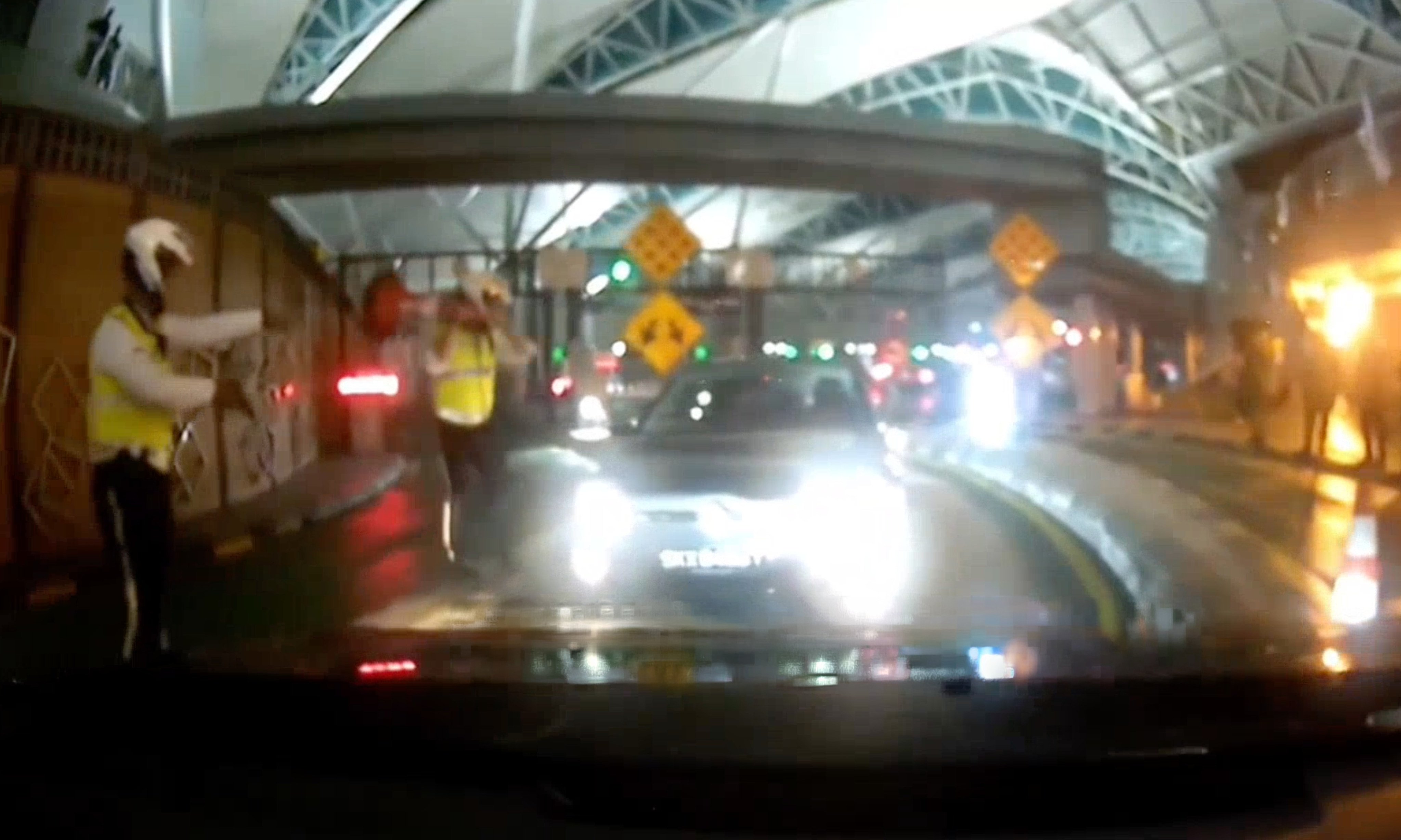 Malaysian police face off with a Singapore-registered car driving against the flow of traffic at the Sultan Iskandar Building immigration complex. The incident occurred last month. Photo: Handout