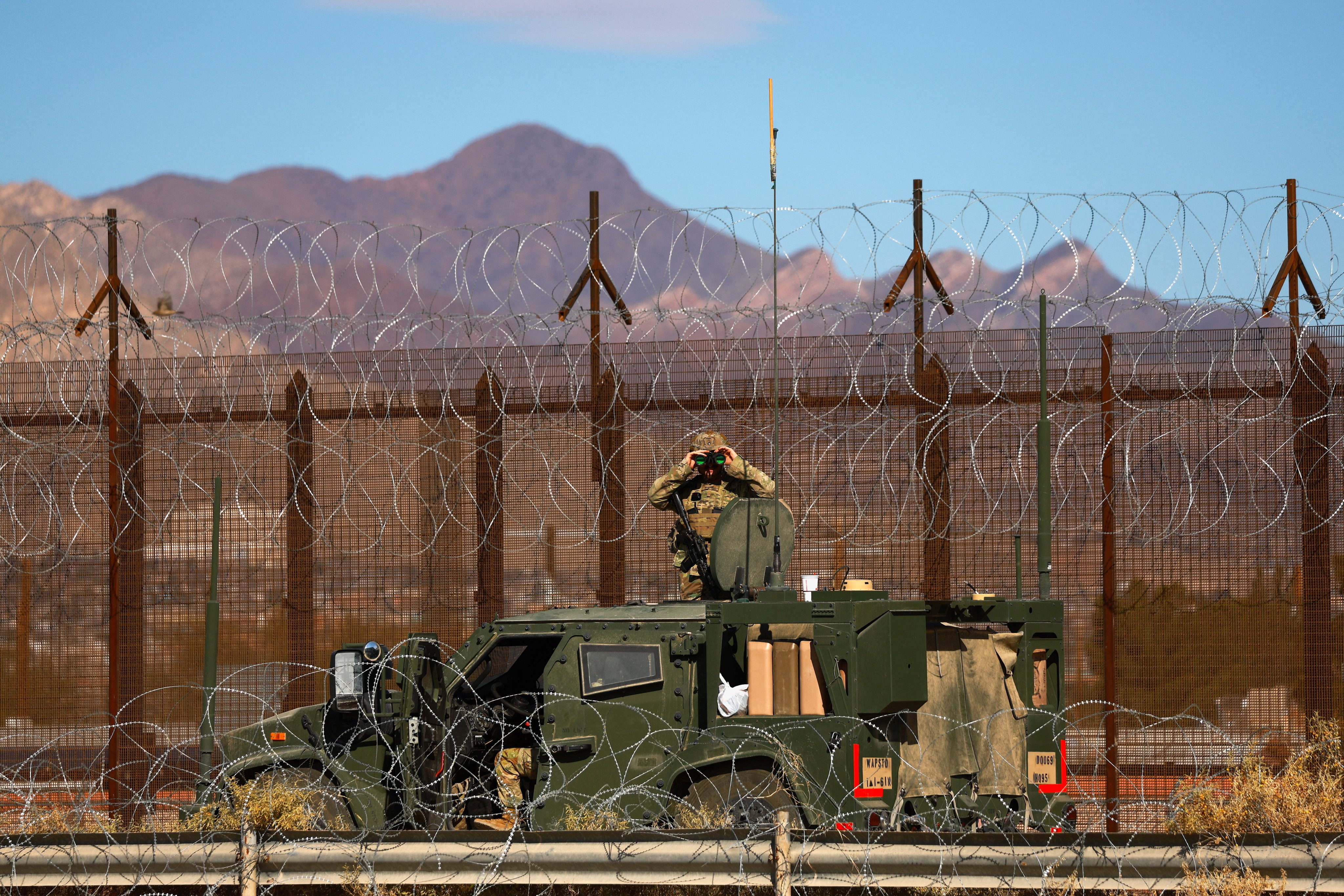 A U.S. military officer uses binoculars while surveilling near the border wall between the United States and Mexico, after Mexican President Claudia Sheinbaum said she ruled out a U.S. military intervention to combat drug cartels, following a “good conversation” on Monday with U.S. President Donald Trump on security and drug trafficking, as seen from Ciudad Juarez, Mexico, January 12, 2026. REUTERS/Jose Luis Gonzalez