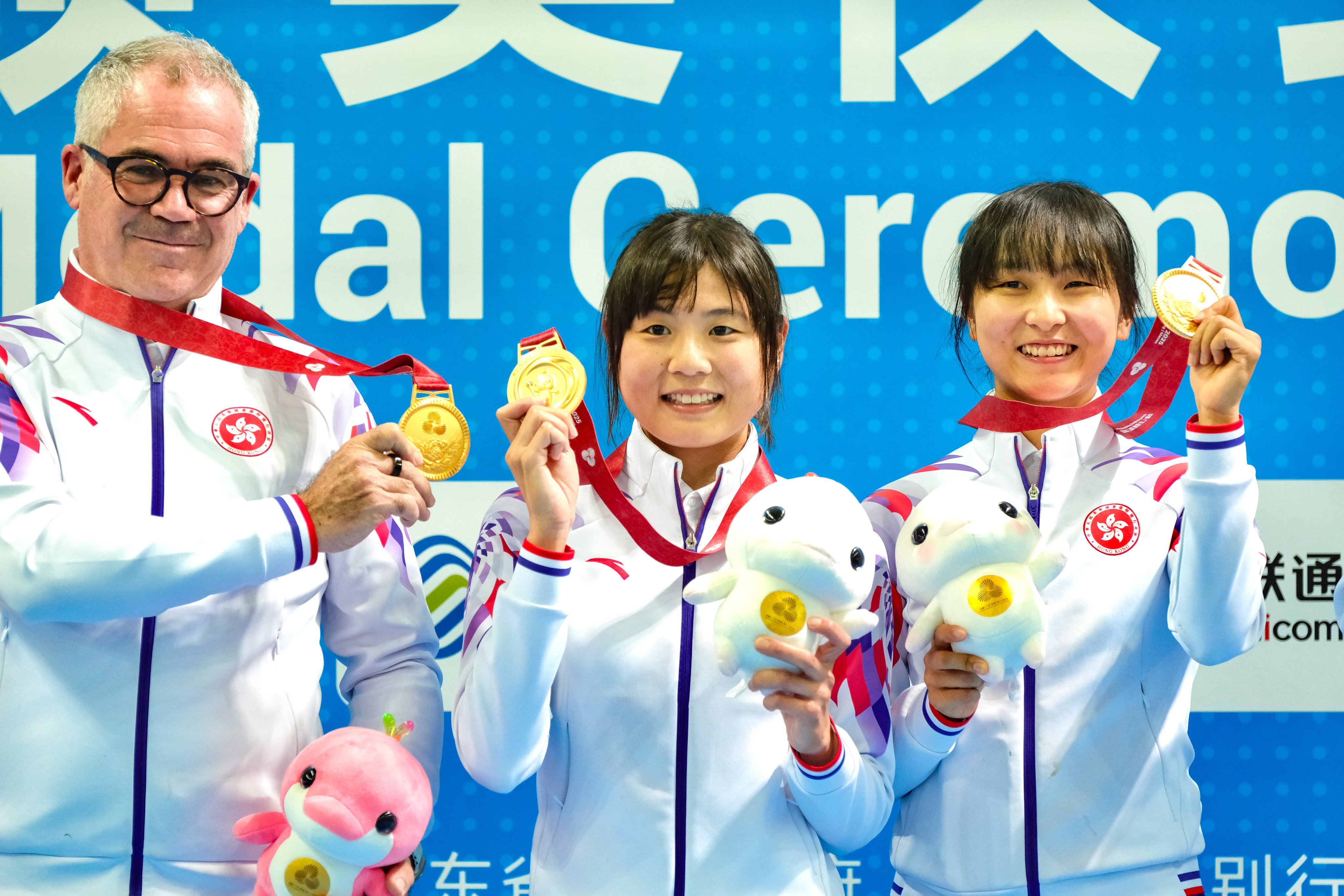Herve Dagorne with leading cyclists Chloe Leung (centre) and Ceci Lee after the pair’s National Games Madison gold. Photo: Karma Lo