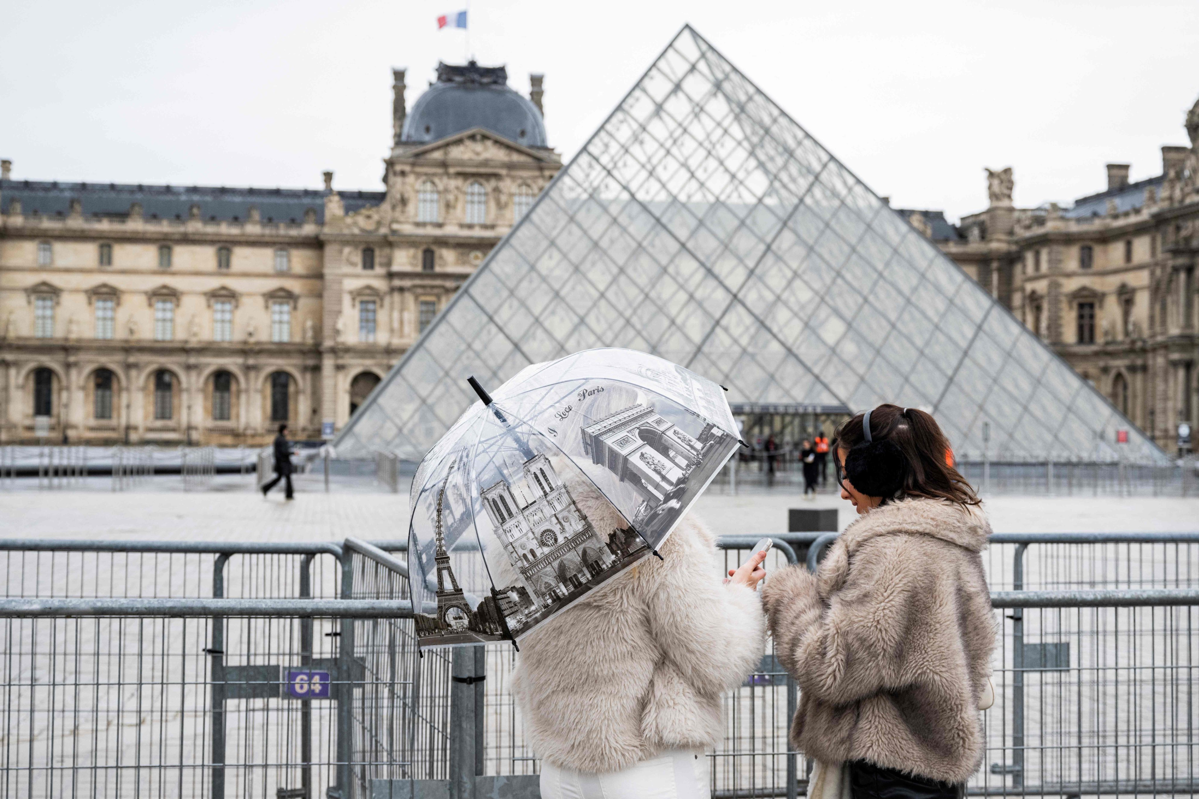 Tourists stand near the Louvre Pyramid, designed by architect I.M. Pei, in Paris in January. Photo: AFP