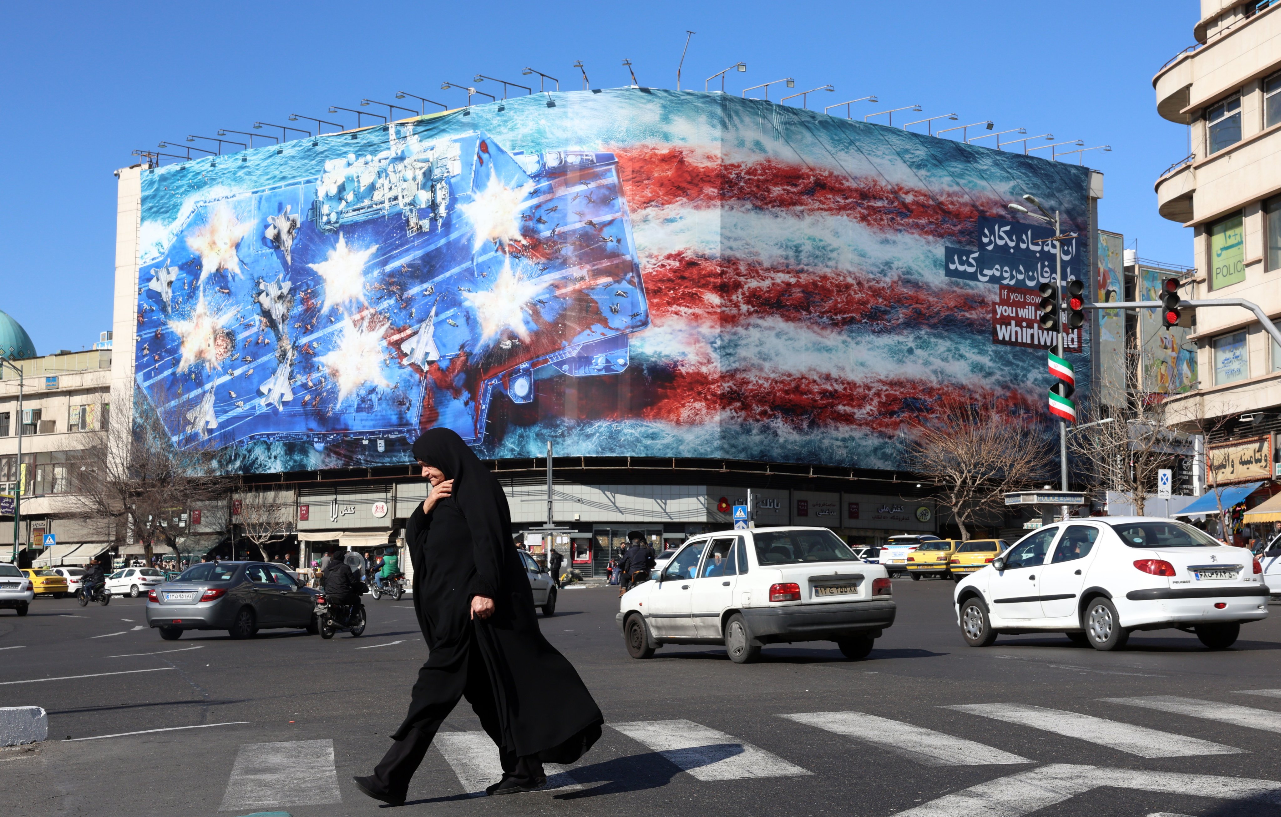 An Iranian woman walk near a huge anti-US billboard hanging at the Enqelab square in Tehran, Iran, on January 31. Photo: EPA-EFE