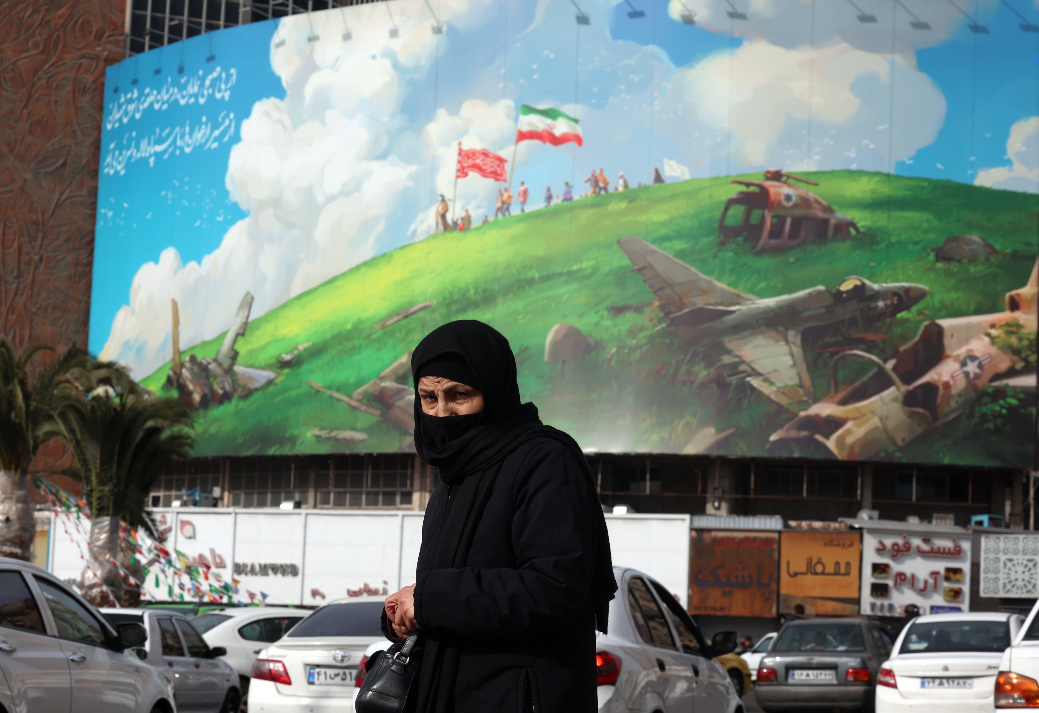 An Iranian woman walks past an anti-US billboard in Tehran, Iran. Photo: EPA
