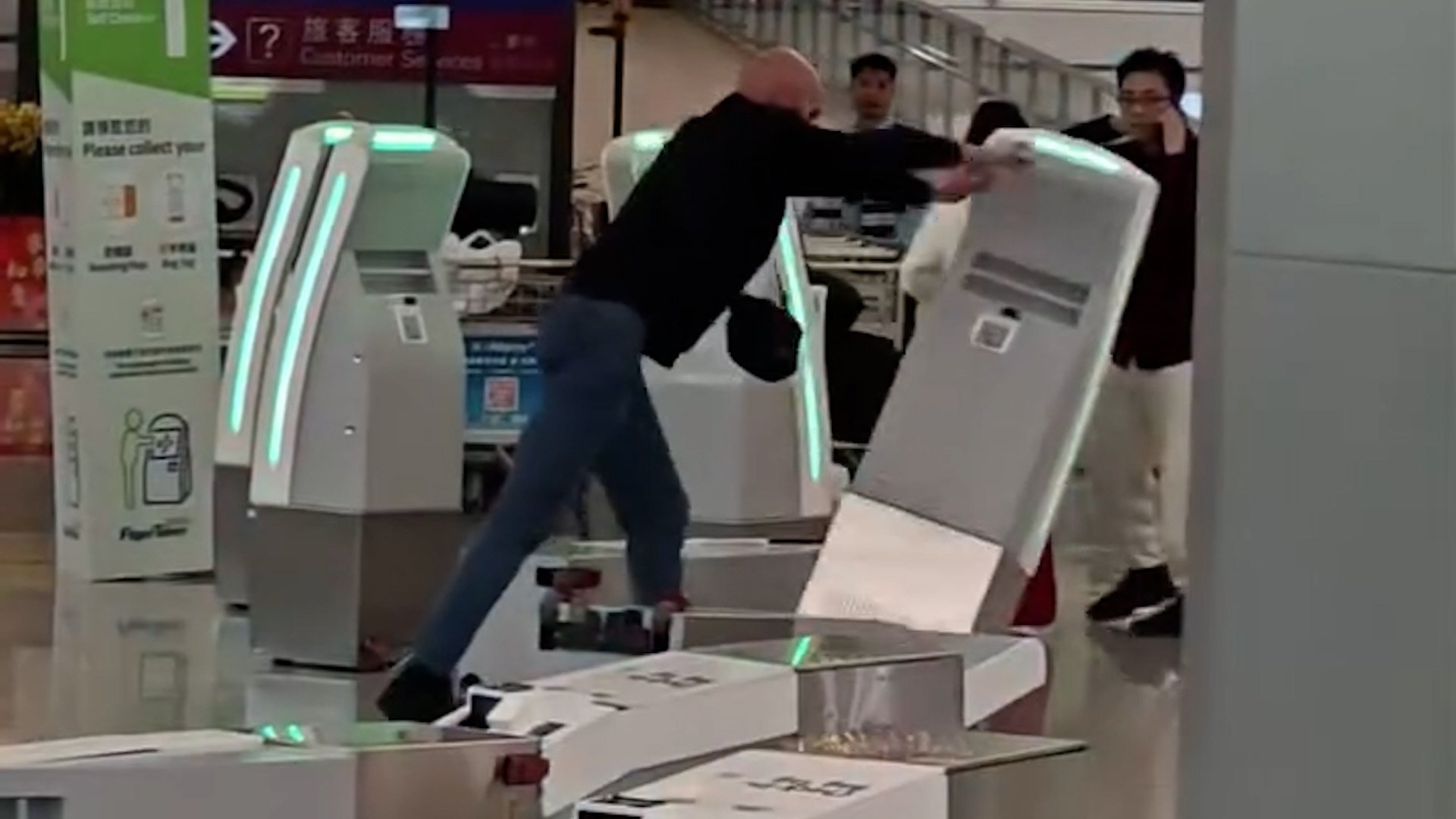 Viral video shows man toppling self-check-in kiosks with a stanchion before being arrested.
