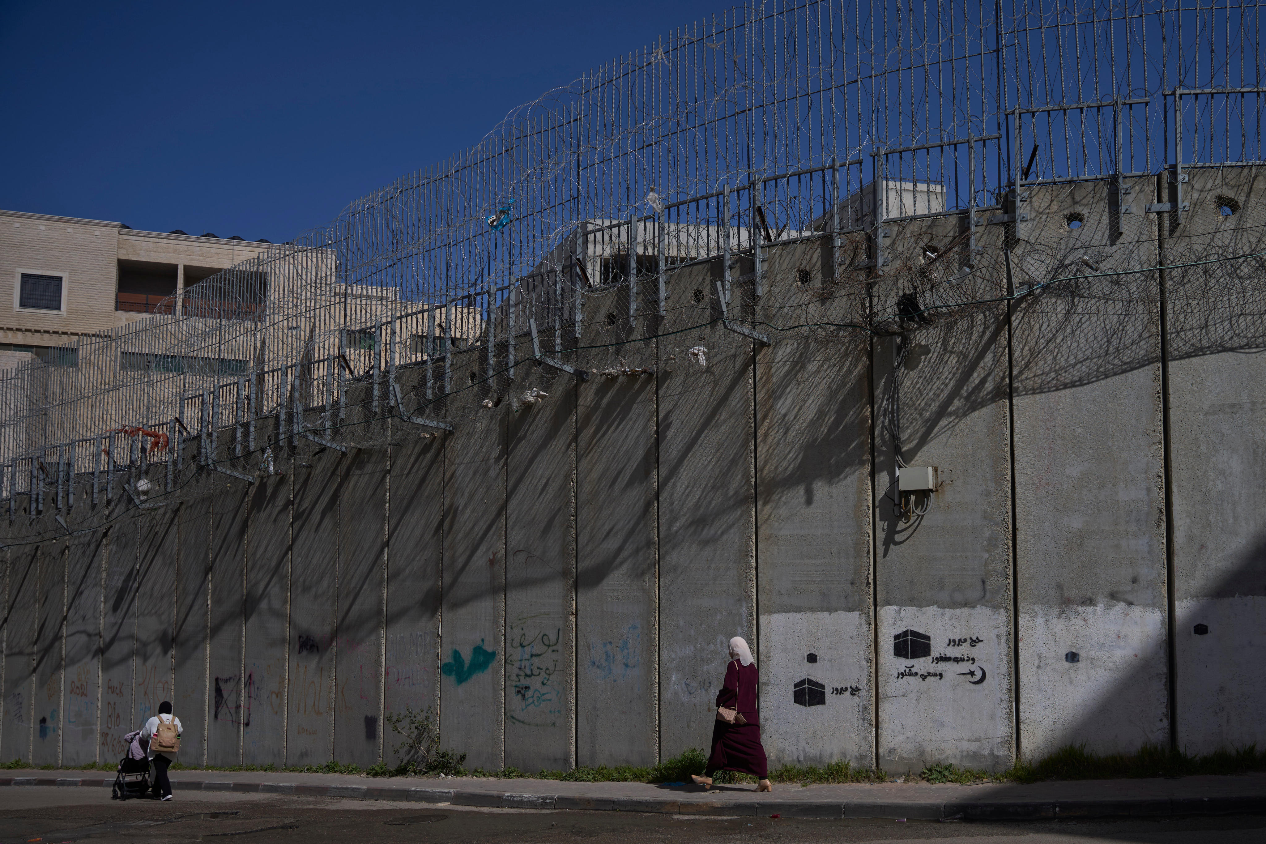 Palestinians walk along the separation barrier between the West Bank and east Jerusalem neighbourhood of Beit Hanina. Photo: AP