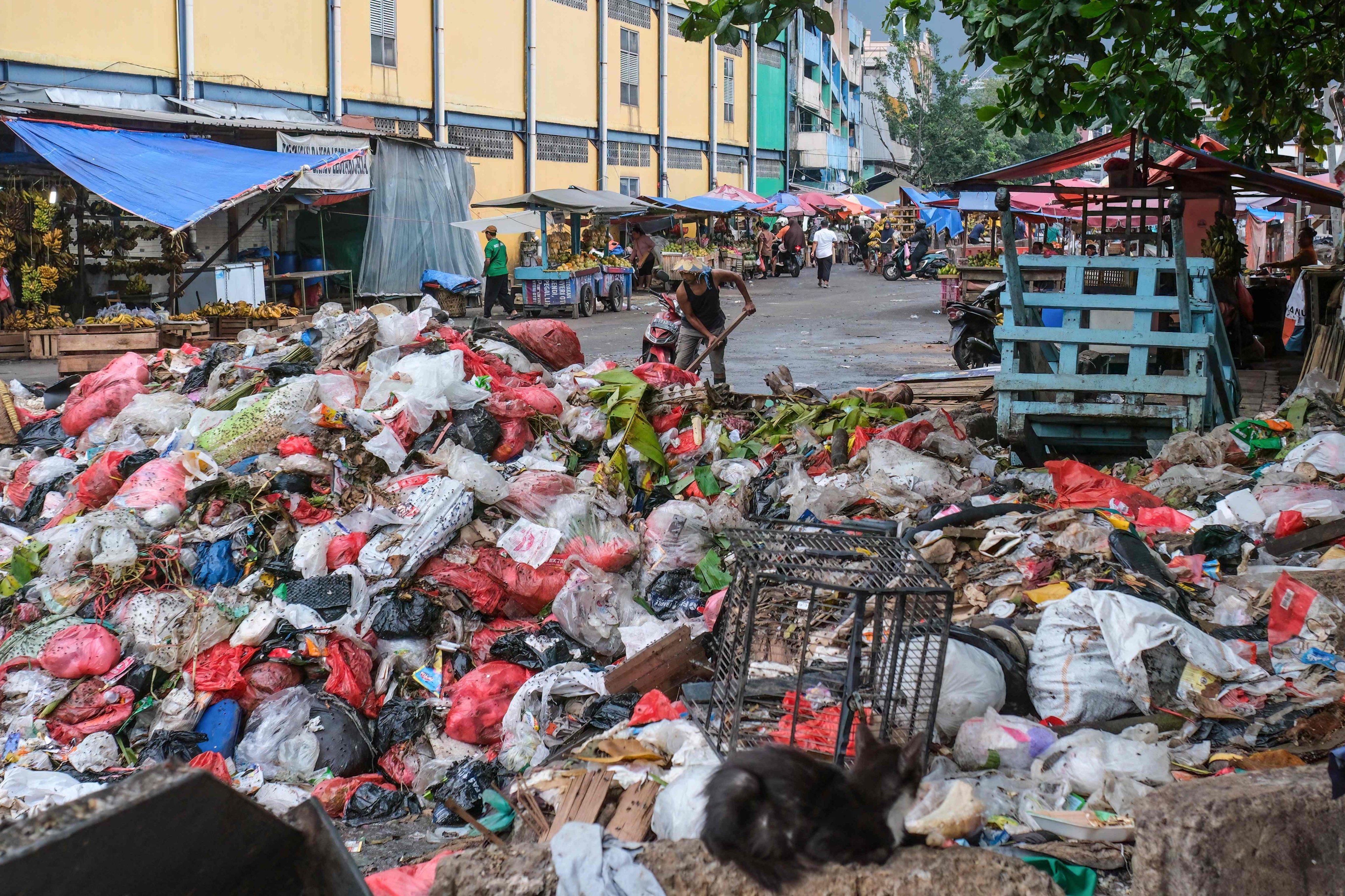 A man uses a shovel on a pile of rubbish on a public road in Pasar Minggu, Jakarta. Photo: AFP