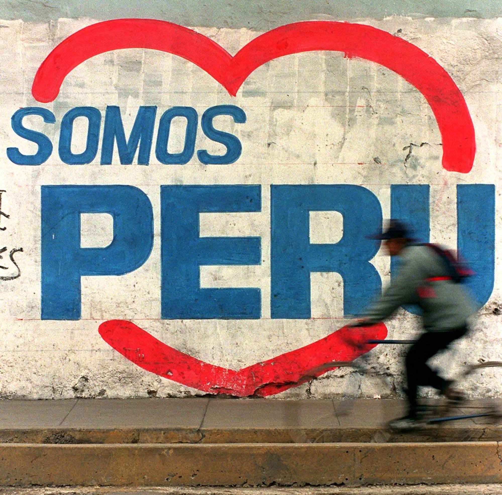 A Lima commuter cycles past a wall covered with graffiti supporting Jeri’s Peruvian political party Somos Peru (We Are Peru). Photo: AFP