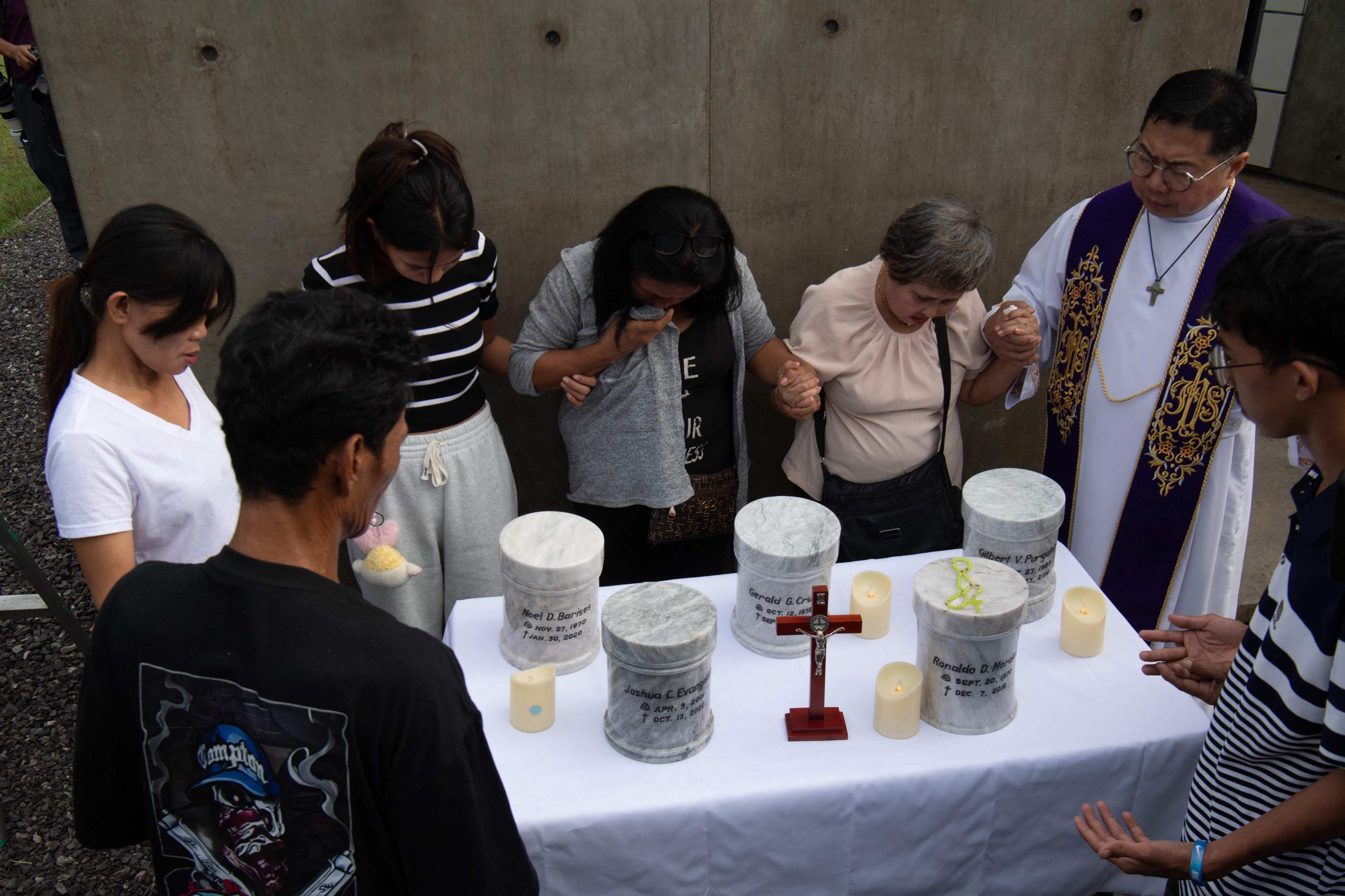 Catholic priest Flavie Villanueva (right) joins hands with relatives of those killed in former Philippine president Rodrigo Duterte’s drug war during inurnment rites on Friday. Photo:  AFP