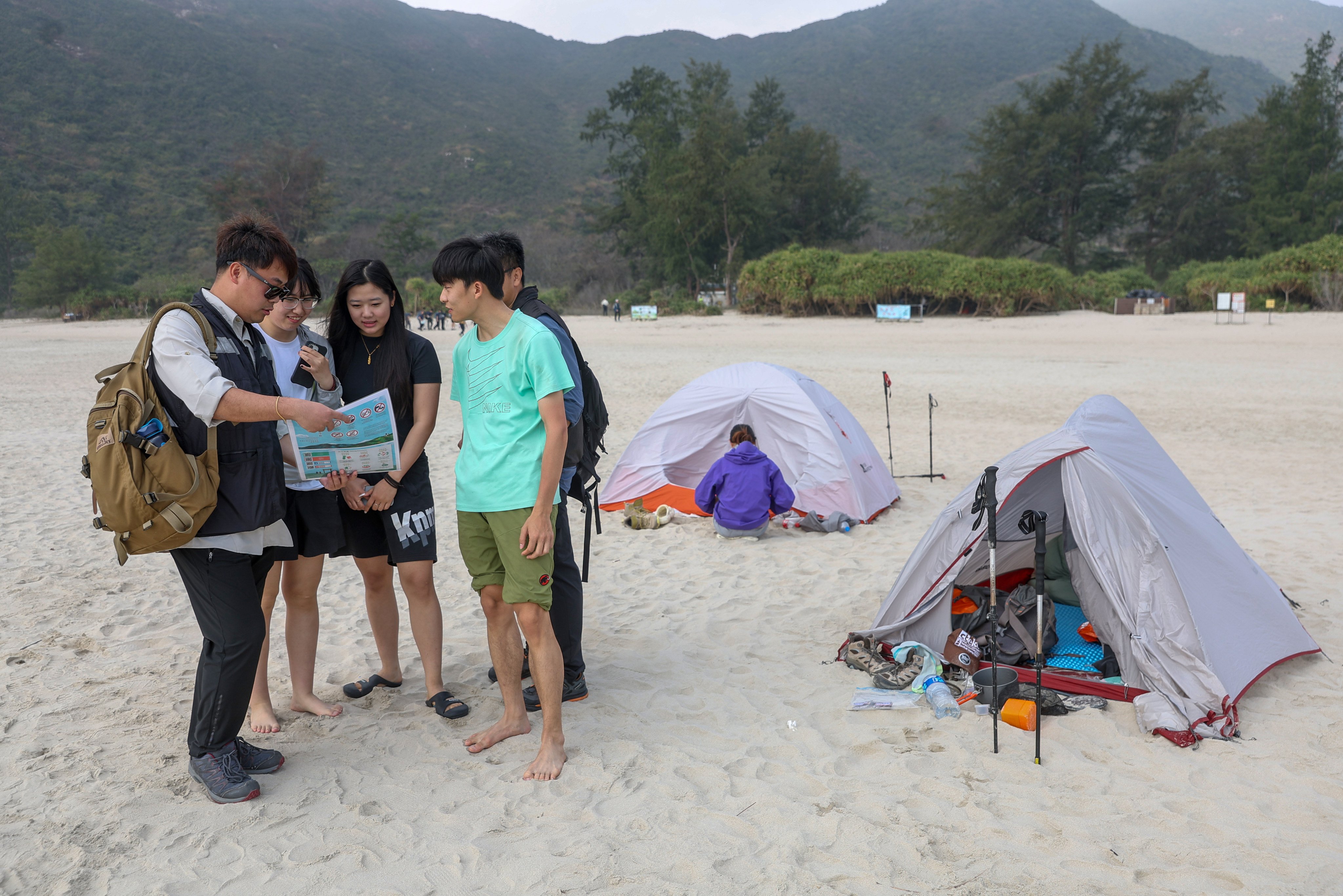 A conservation officer reminds visitors to keep the environment clean at Ham Tin Wan in Sai Kung. Photo: Edmond So