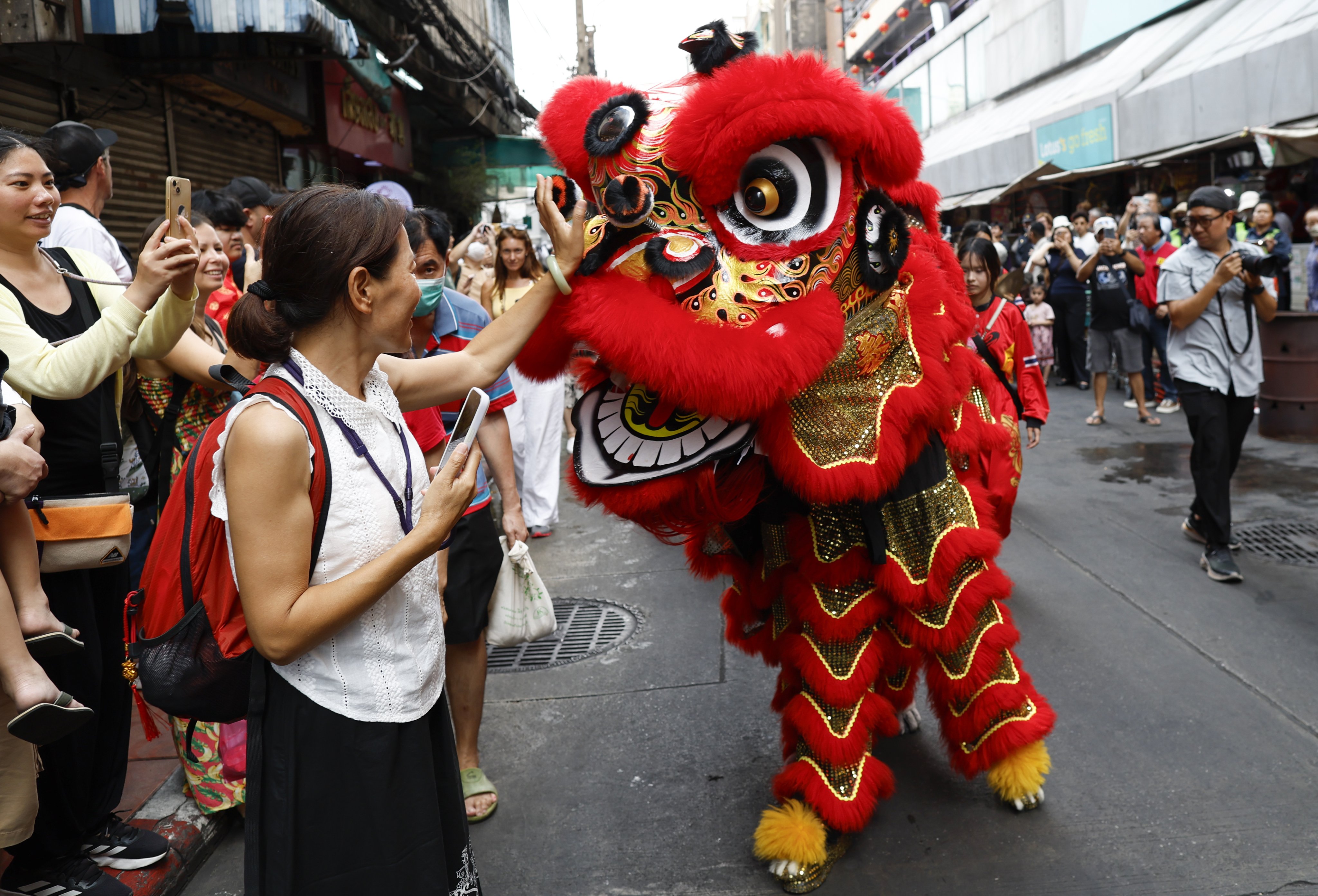A tourist interacts with a lion dance performer in Bangkok’s Chinatown, Thailand, on Monday. Photo: EPA