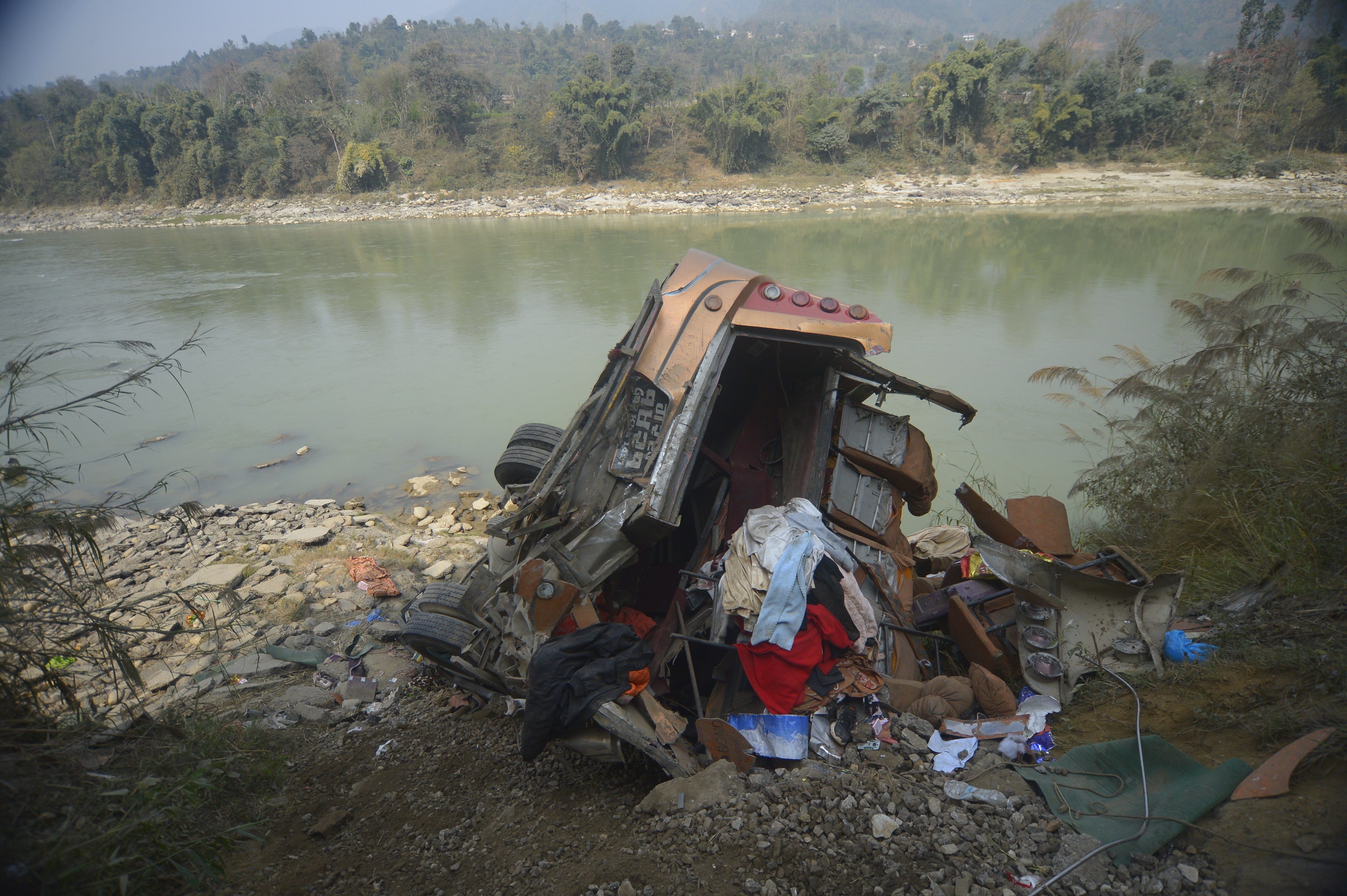 The bus rolled down a mountain slope and landed on the banks of a river. Photo: AP