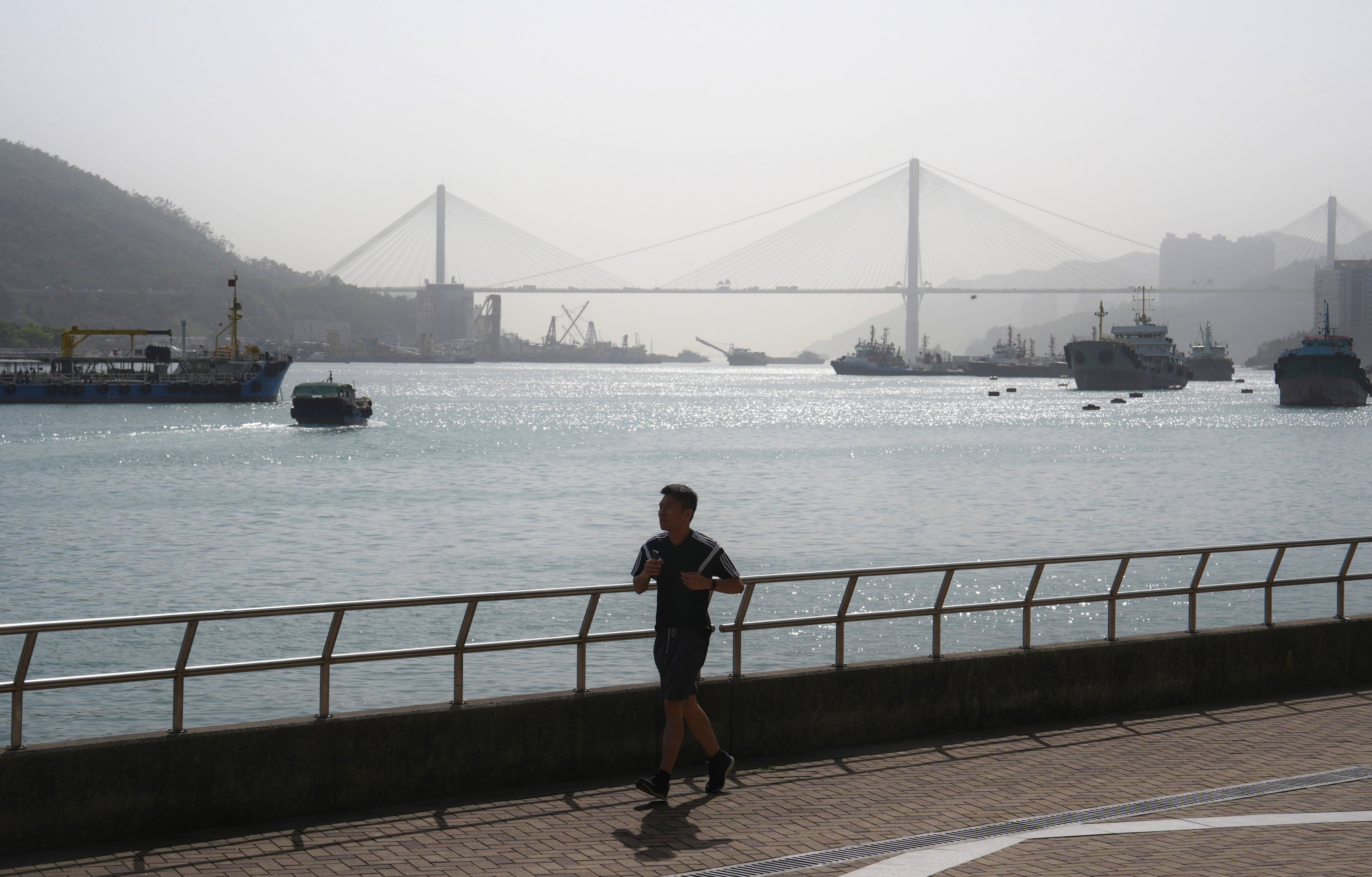A man jogs along the Tsuen Wan Promenade, with Ting Kau Bridge in the background, on April 15. Photo: Elson Li