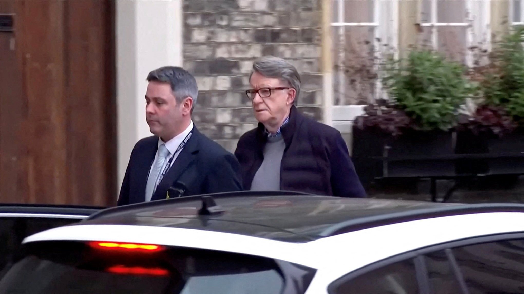 Peter Mandelson being led away from his home by a police officer. Photo: BBC via Reuters