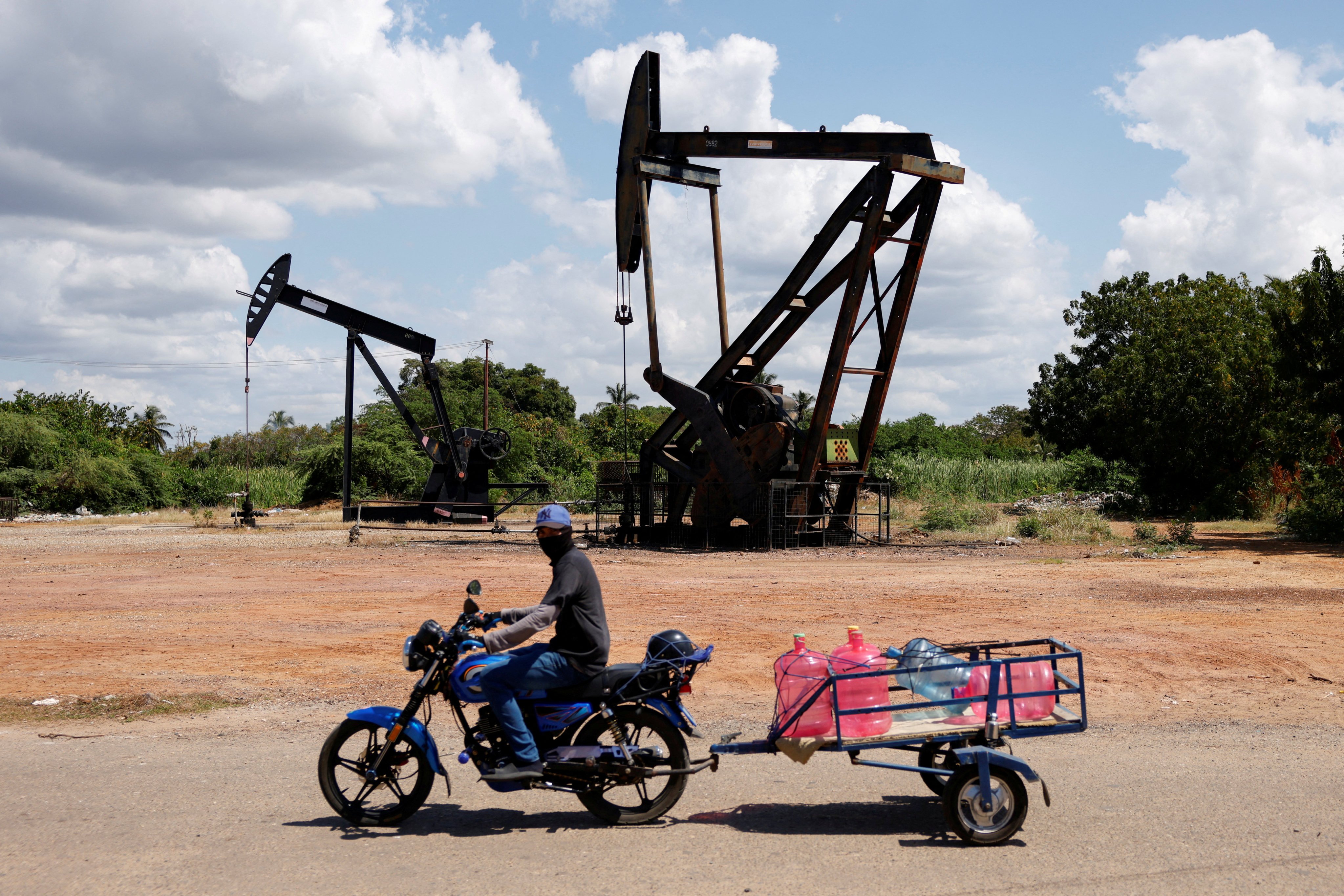 A man on a motorcycle transports water bottles past pumpjacks, beside deteriorating oil infrastructure on the shores of Lake Maracaibo, in Cabimas, Venezuela on January 26. Photo: Reuters