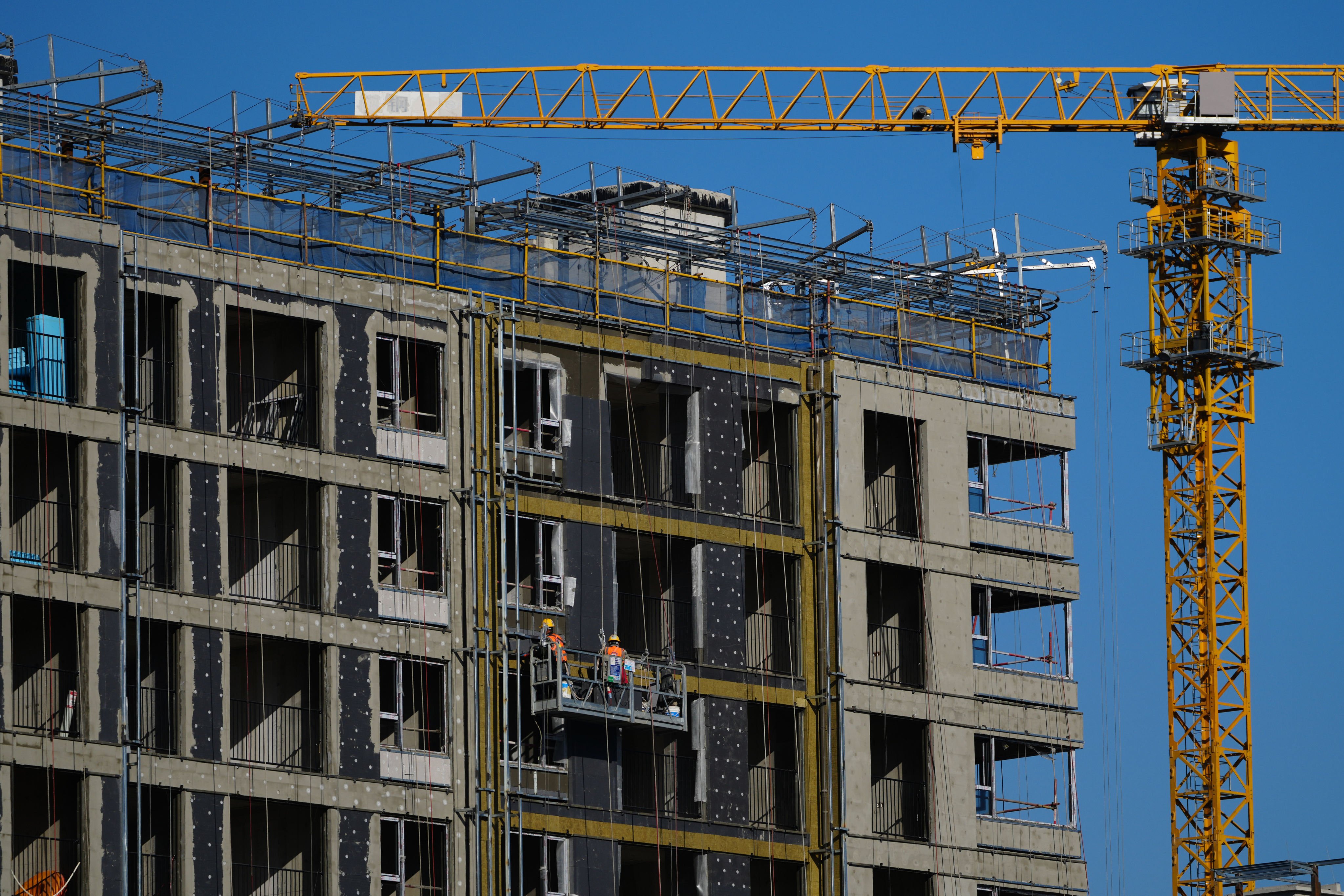 Workers install insulation on a residential building under construction in Beijing in December. Photo: AP