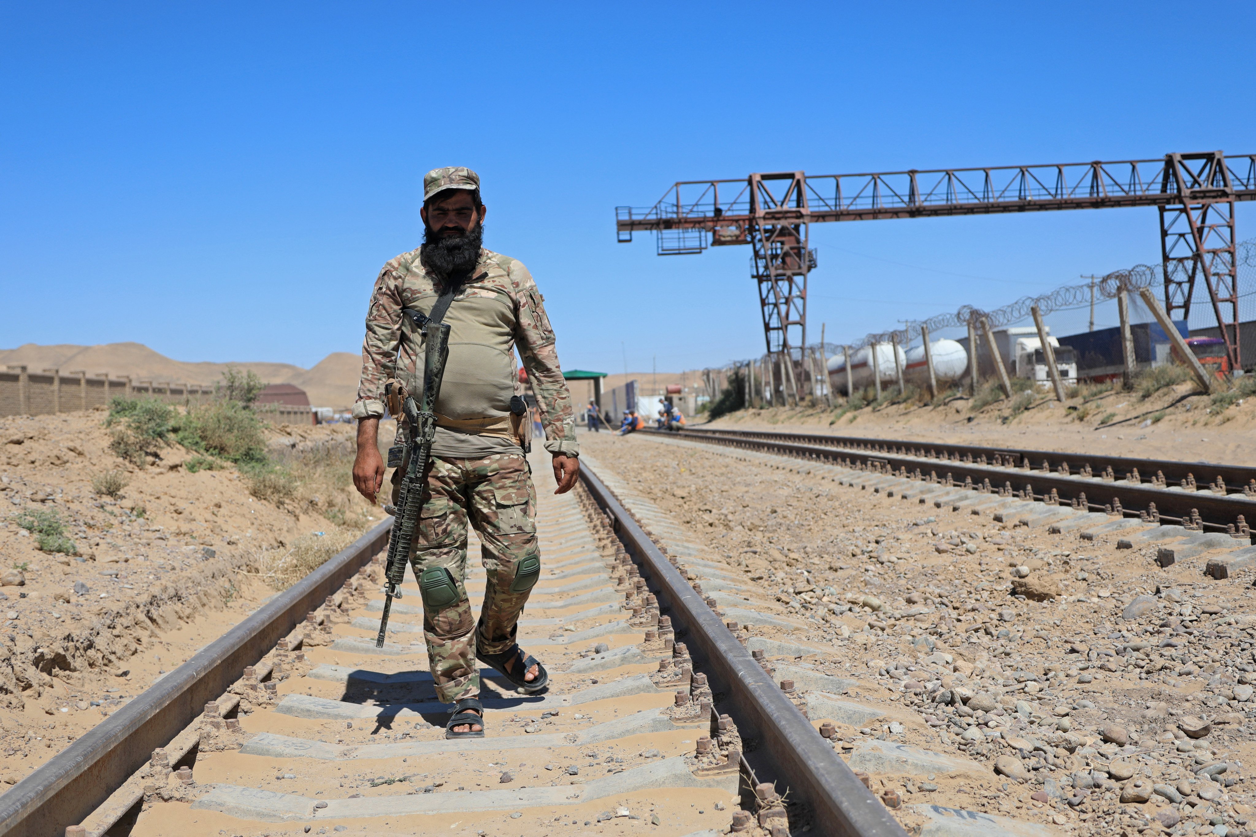 A Taliban guard walks along railway tracks near a TAPI pipeline construction site at the Afghanistan-Turkmenistan border in 2024. Photo: AFP